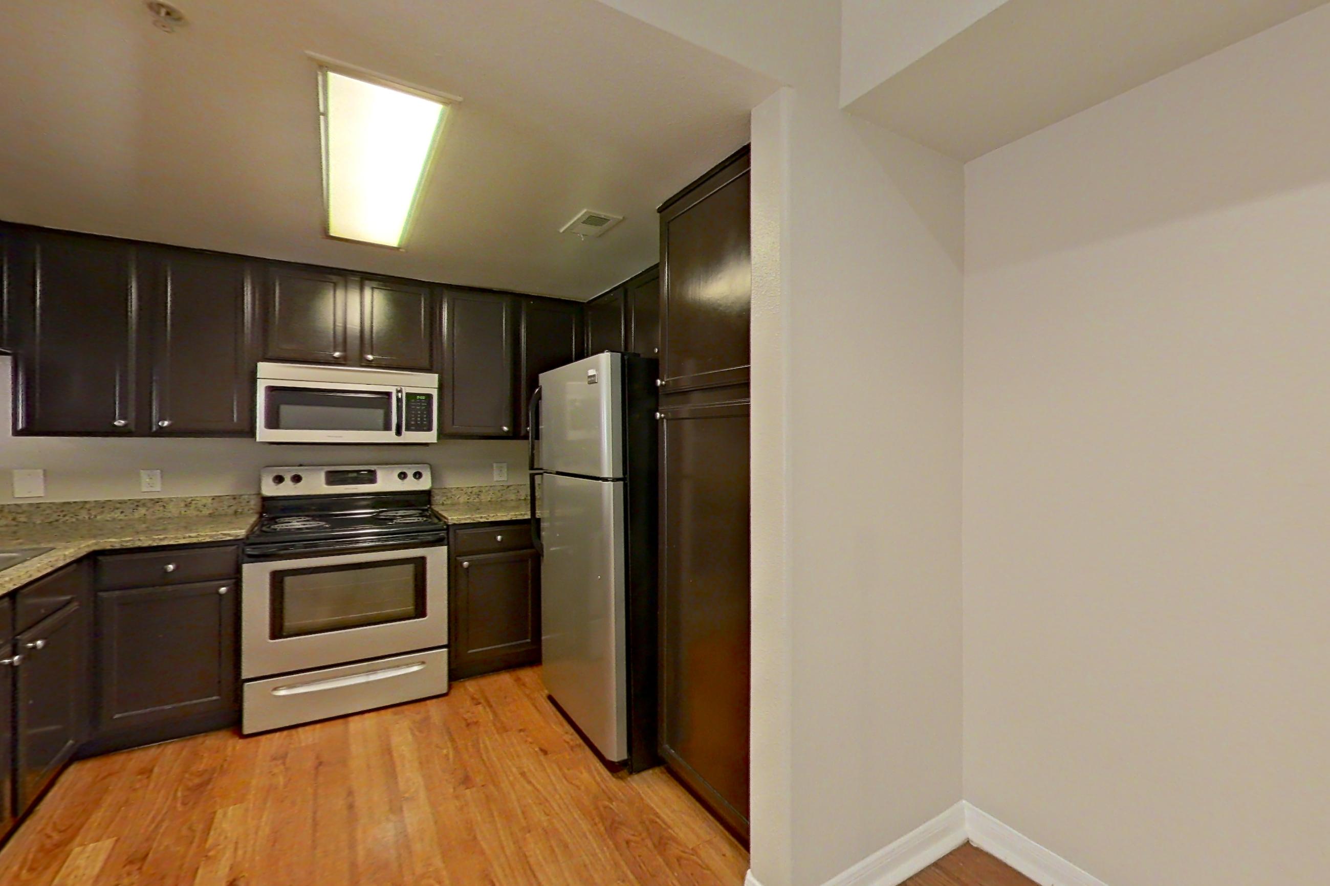 Dining room with electric range, fireplace, light stone countertops, light wood-finish flooring, microwave, oven/range, refrigerator, stainless steel appliances, and wood-finish flooring, Apartment 0927 at Marquis on Westheimer