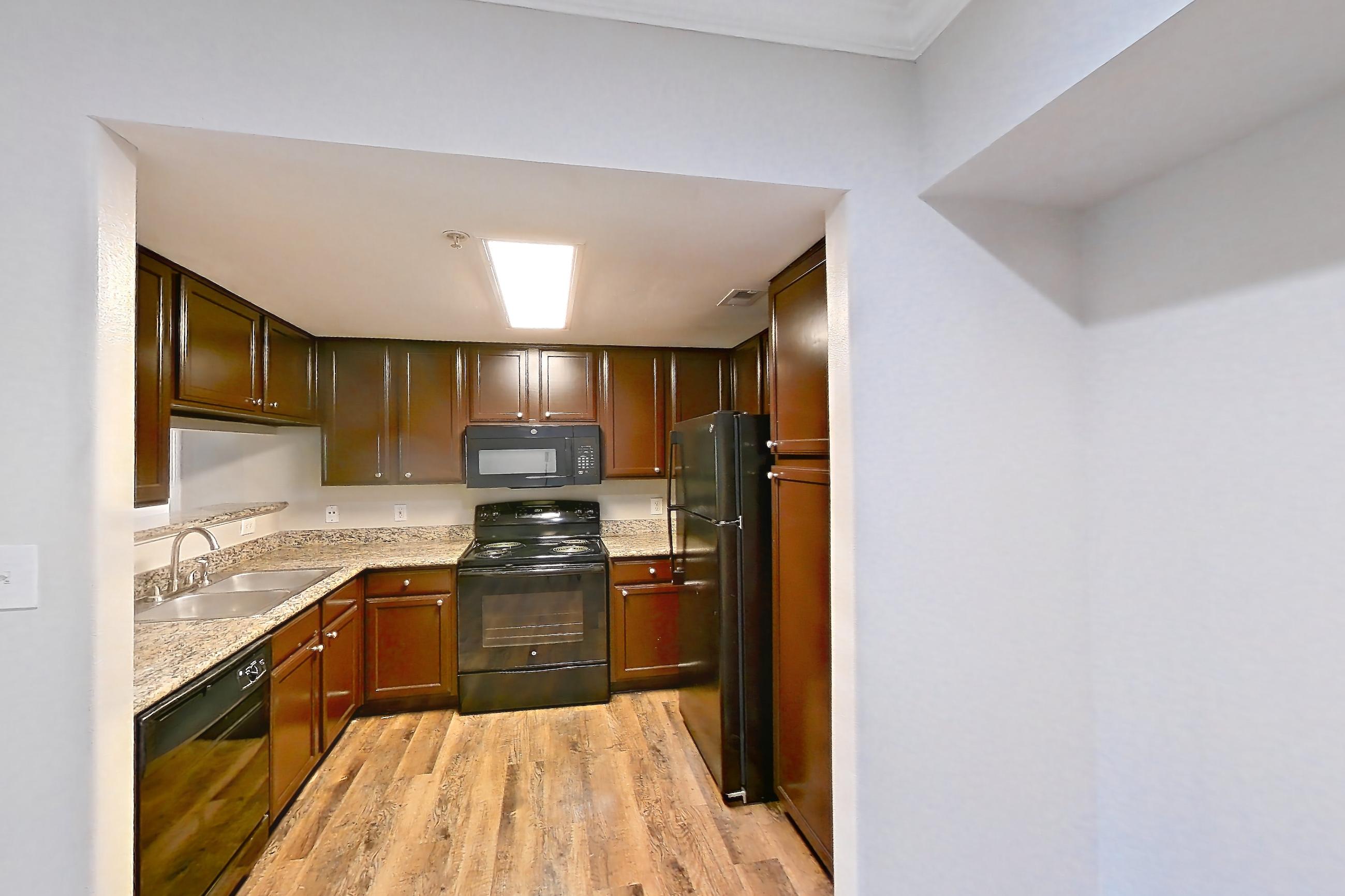 Dining room with black appliances, dark wood-finish flooring, electric range, light stone countertops, light wood-finish flooring, microwave, oven/range, and refrigerator, Apartment 0933 at Marquis on Westheimer
