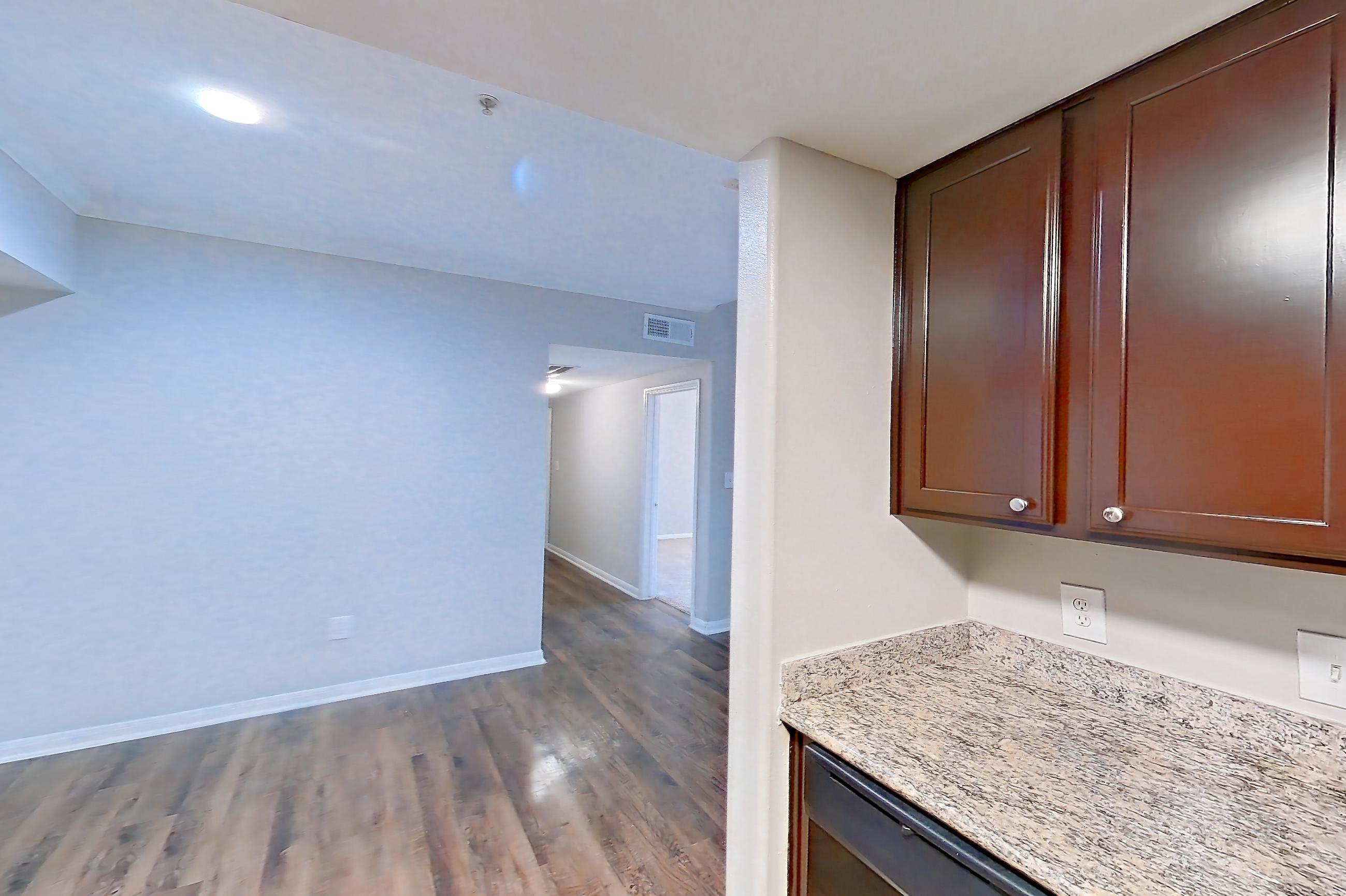 Kitchen with black appliances, dishwasher, electric range, glass shower door, light stone countertops, light wood-finish flooring, microwave, oven/range, refrigerator, stall shower, and walk-in shower, Apartment 0933 at Marquis on Westheimer