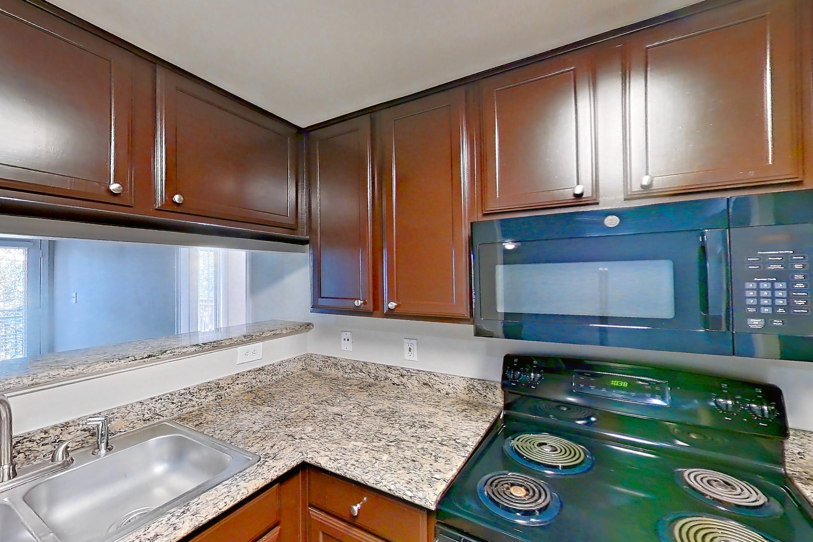 Kitchen with black appliances, dishwasher, electric range, glass shower door, light stone countertops, light wood-finish flooring, microwave, oven/range, refrigerator, stall shower, and walk-in shower, Apartment 0933 at Marquis on Westheimer
