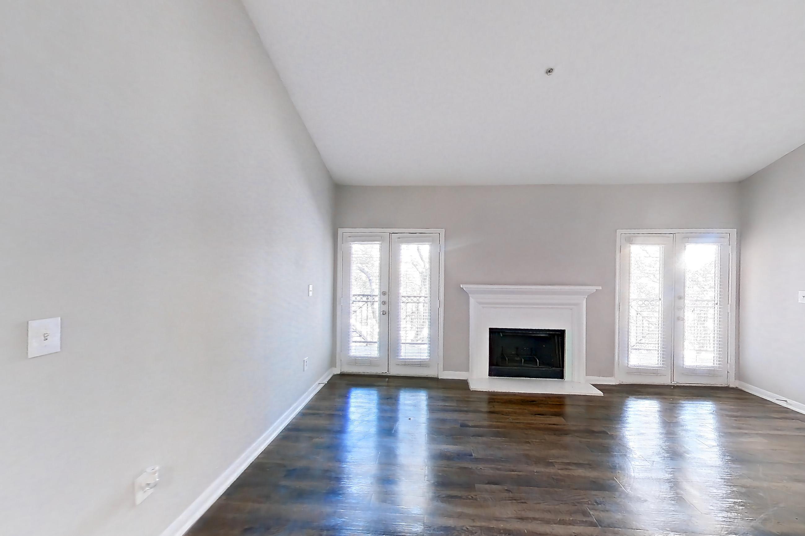 Living space with black appliances, fireplace, light wood-finish flooring, and refrigerator, Apartment 0933 at Marquis on Westheimer