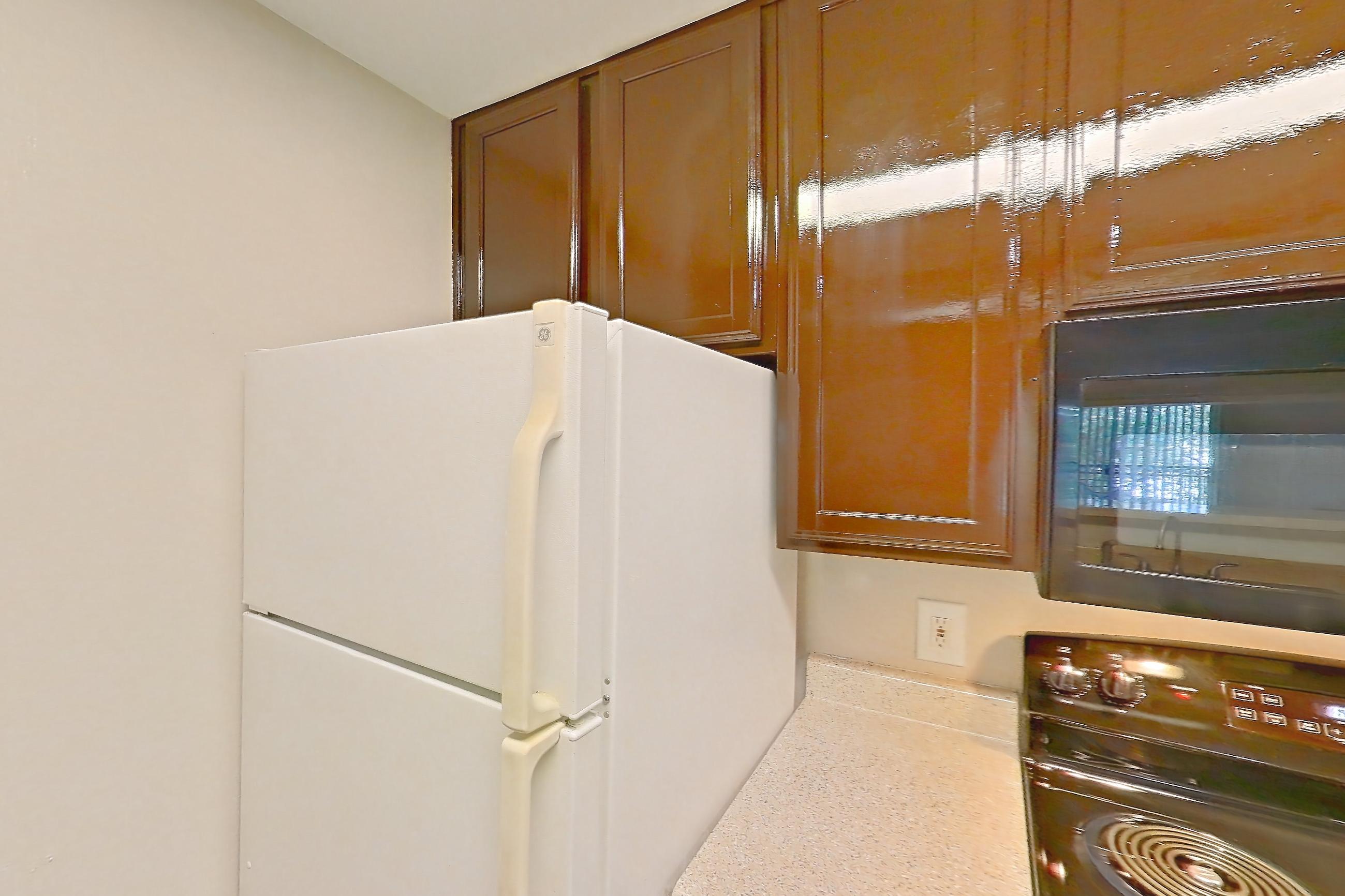 Kitchen with black appliances, dishwasher, electric range, light countertops, light stone countertops, light wood-finish flooring, microwave, oven/range, refrigerator, and white appliances, Apartment 0934 at Marquis on Westheimer