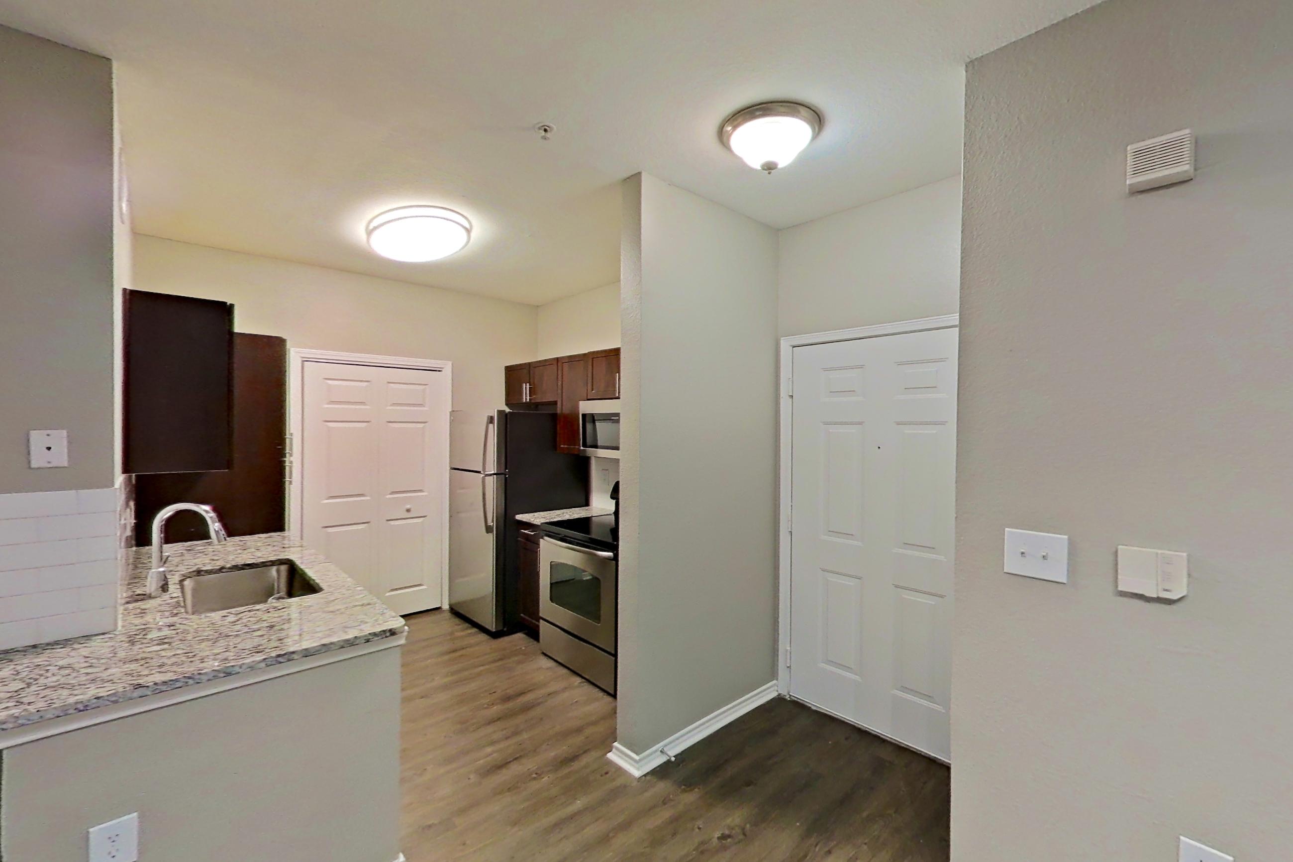 Dining room with dark wood-finish flooring, electric range, light stone countertops, oven/range, refrigerator, and stainless steel appliances, Apartment 05-00512 at Marquis on Gaston