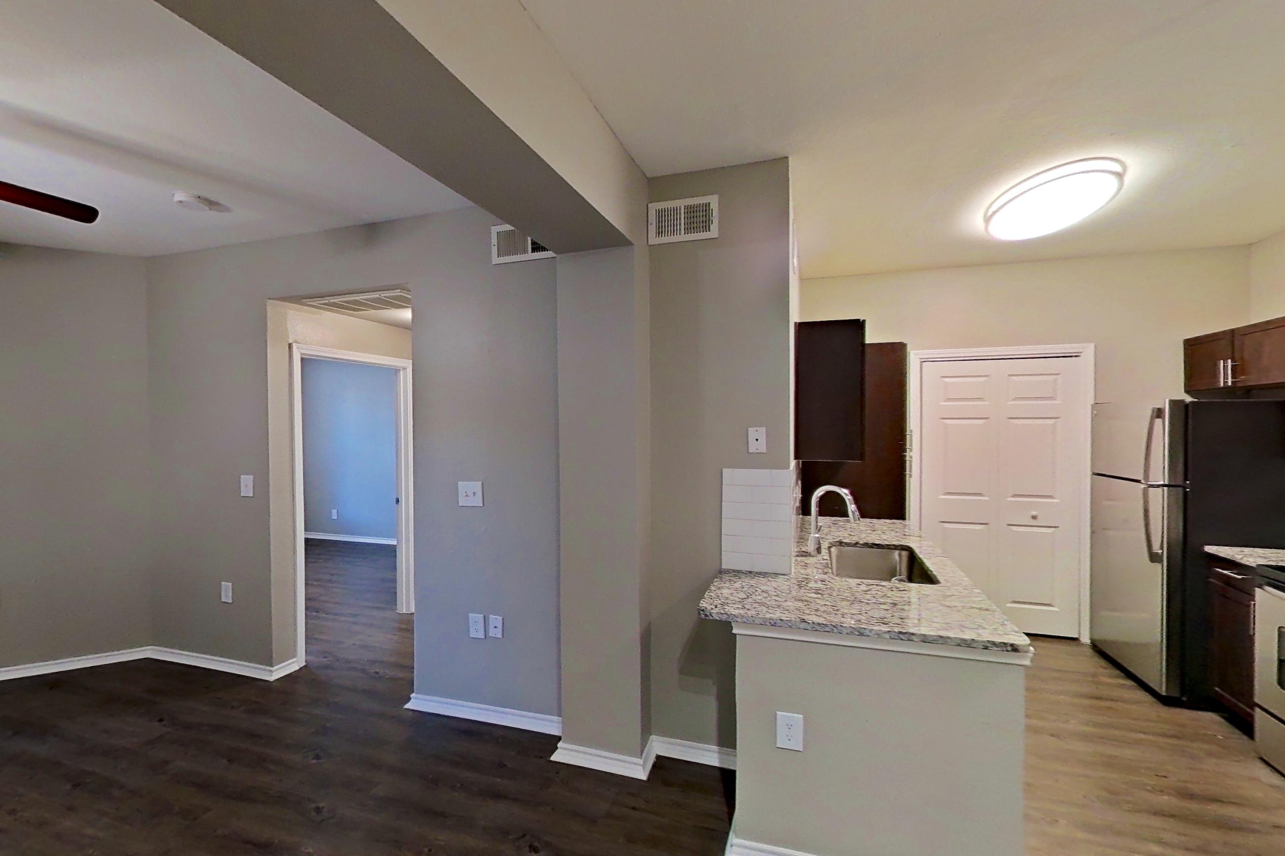 Dining room with dark wood-finish flooring, electric range, light stone countertops, oven/range, refrigerator, and stainless steel appliances, Apartment 05-00512 at Marquis on Gaston