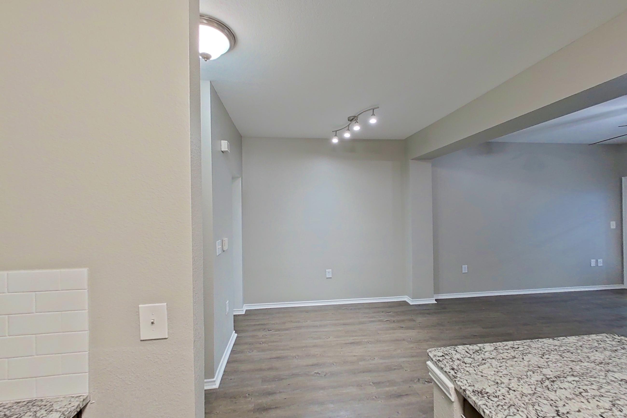 Kitchen with dishwasher, electric range, finished basement, light stone countertops, light wood-finish flooring, microwave, oven/range, and stainless steel appliances, Apartment 05-00512 at Marquis on Gaston