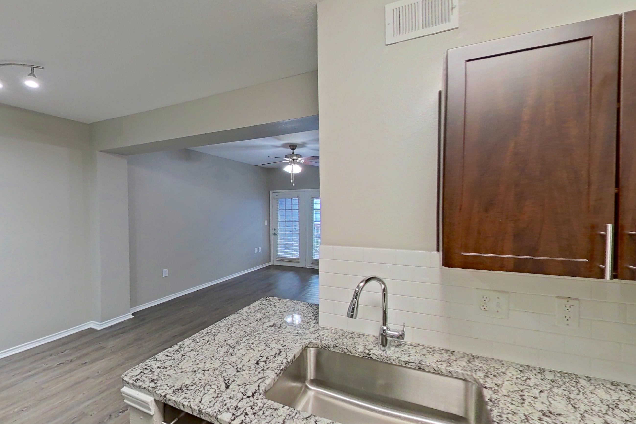 Kitchen with dishwasher, electric range, finished basement, light stone countertops, light wood-finish flooring, microwave, oven/range, and stainless steel appliances, Apartment 05-00512 at Marquis on Gaston