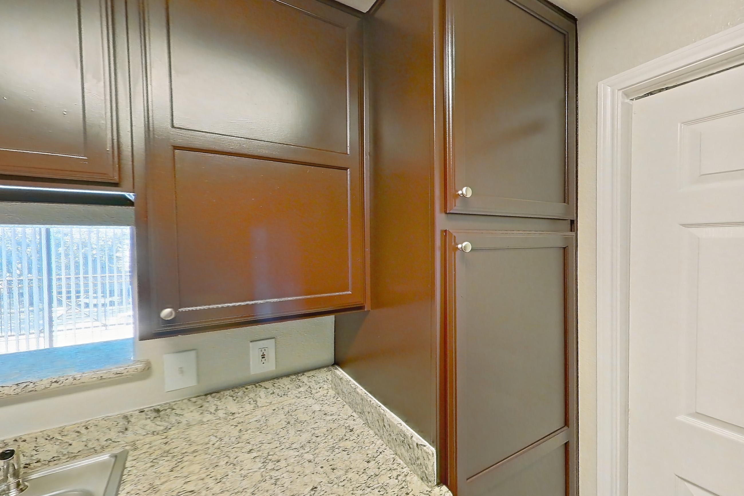 Kitchen with black appliances, dishwasher, electric range, light stone countertops, light wood-finish flooring, microwave, oven/range, refrigerator, and stainless steel appliances, Apartment 1138 at Marquis on Westheimer