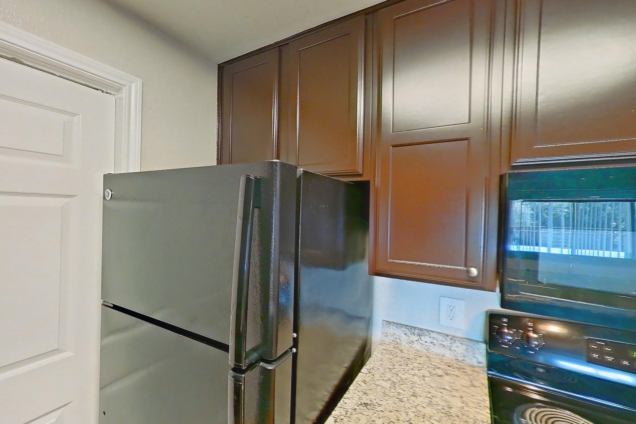 Kitchen with black appliances, dishwasher, electric range, light stone countertops, light wood-finish flooring, microwave, oven/range, refrigerator, and stainless steel appliances, Apartment 1138 at Marquis on Westheimer