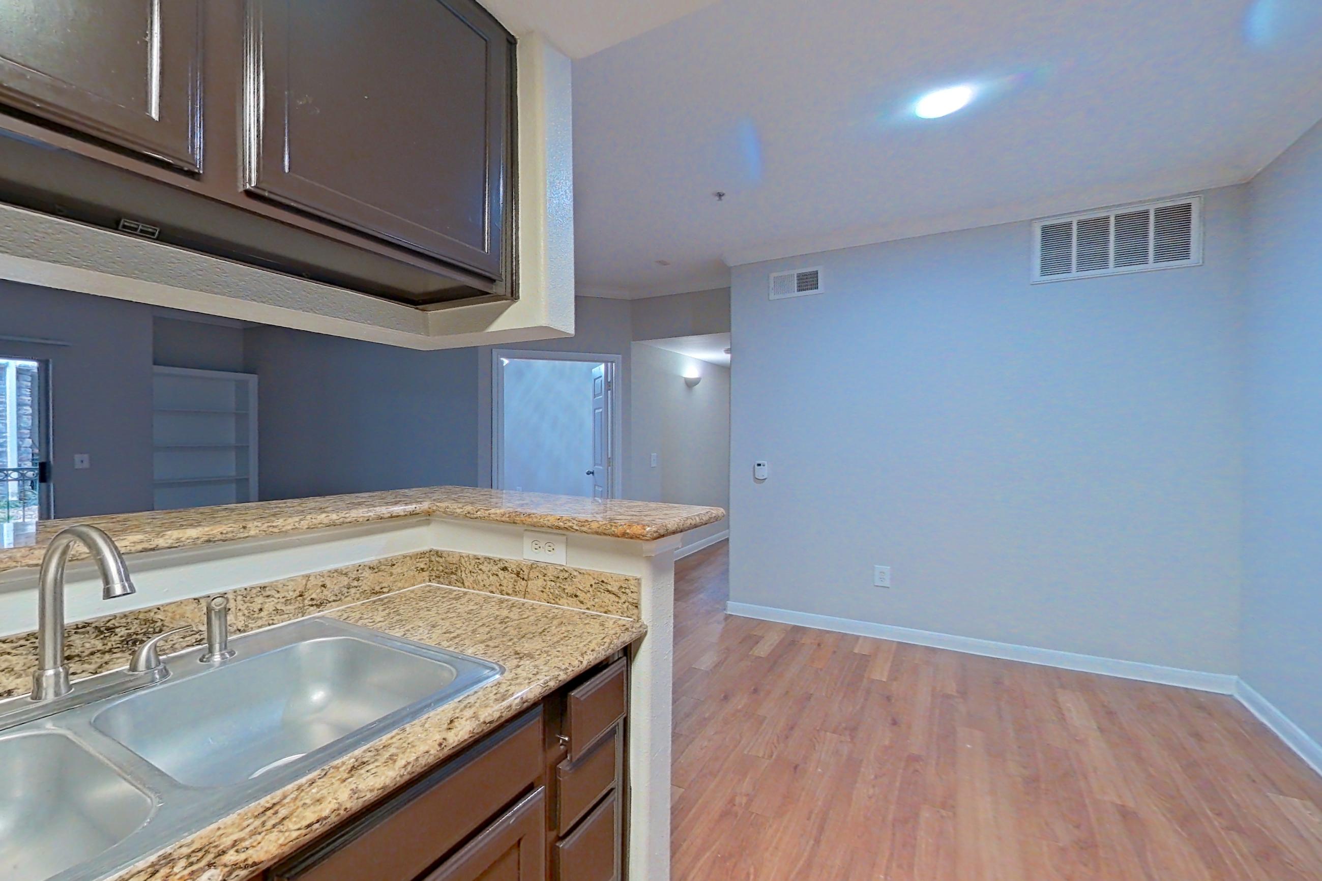 Kitchen with black appliances, dishwasher, electric range, light stone countertops, light wood-finish flooring, oven/range, refrigerator, and stainless steel appliances, Apartment 1217 at Marquis on Westheimer
