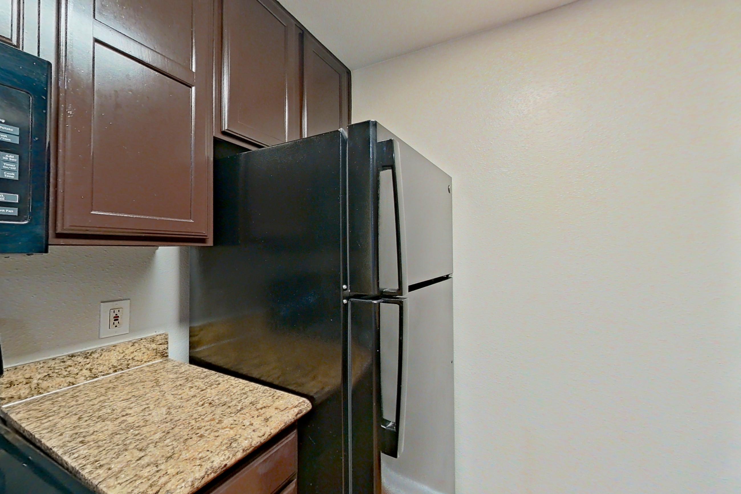 Kitchen with black appliances, dishwasher, electric range, light stone countertops, light wood-finish flooring, oven/range, refrigerator, and stainless steel appliances, Apartment 1217 at Marquis on Westheimer