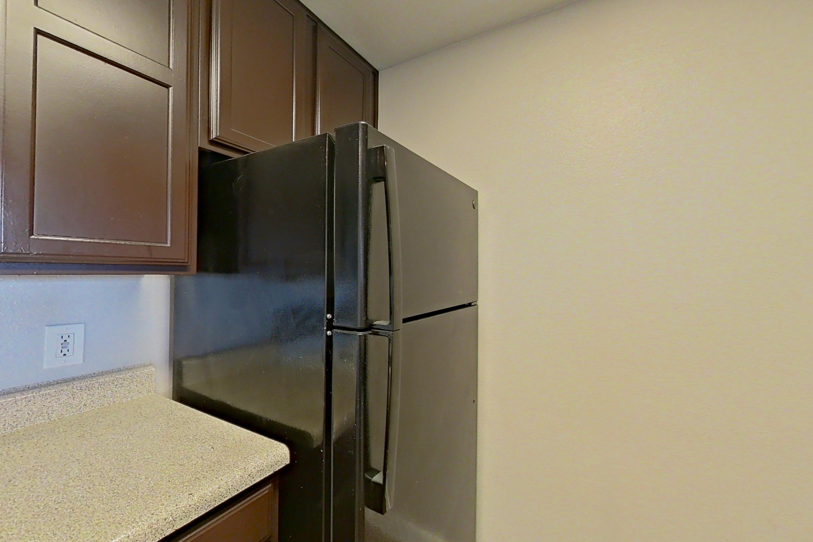 Kitchen with black appliances, dishwasher, light countertops, light stone countertops, refrigerator, and white appliances, Apartment 1223 at Marquis on Westheimer