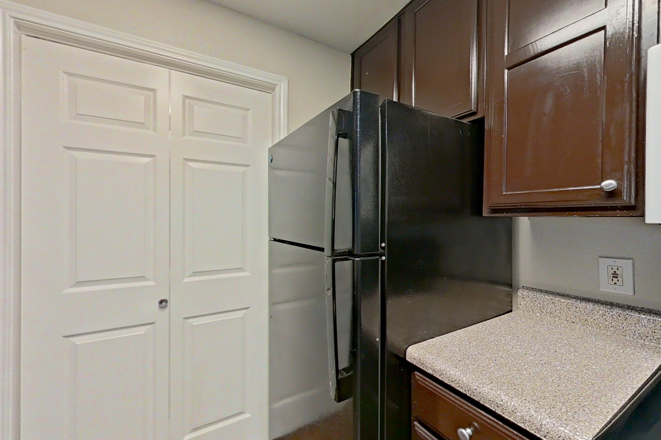 Kitchen with black appliances, dark wood-finish flooring, light countertops, oven/range, and refrigerator, Apartment 1228 at Marquis on Westheimer