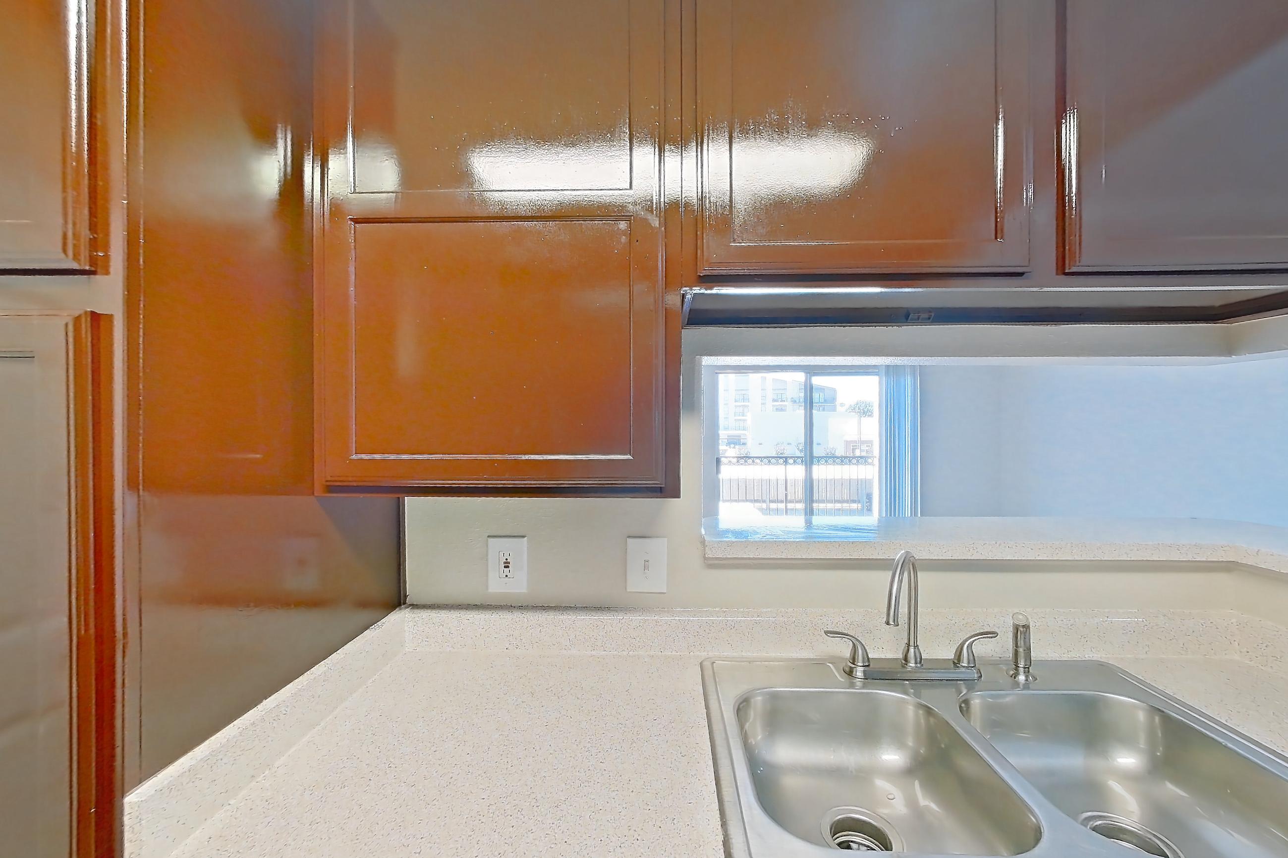 Kitchen with black appliances, dishwasher, electric range, light countertops, light stone countertops, light wood-finish flooring, oven/range, range hood, refrigerator, stainless steel appliances, white appliances, and wood-finish flooring, Apartment 1325 at Marquis on Westheimer