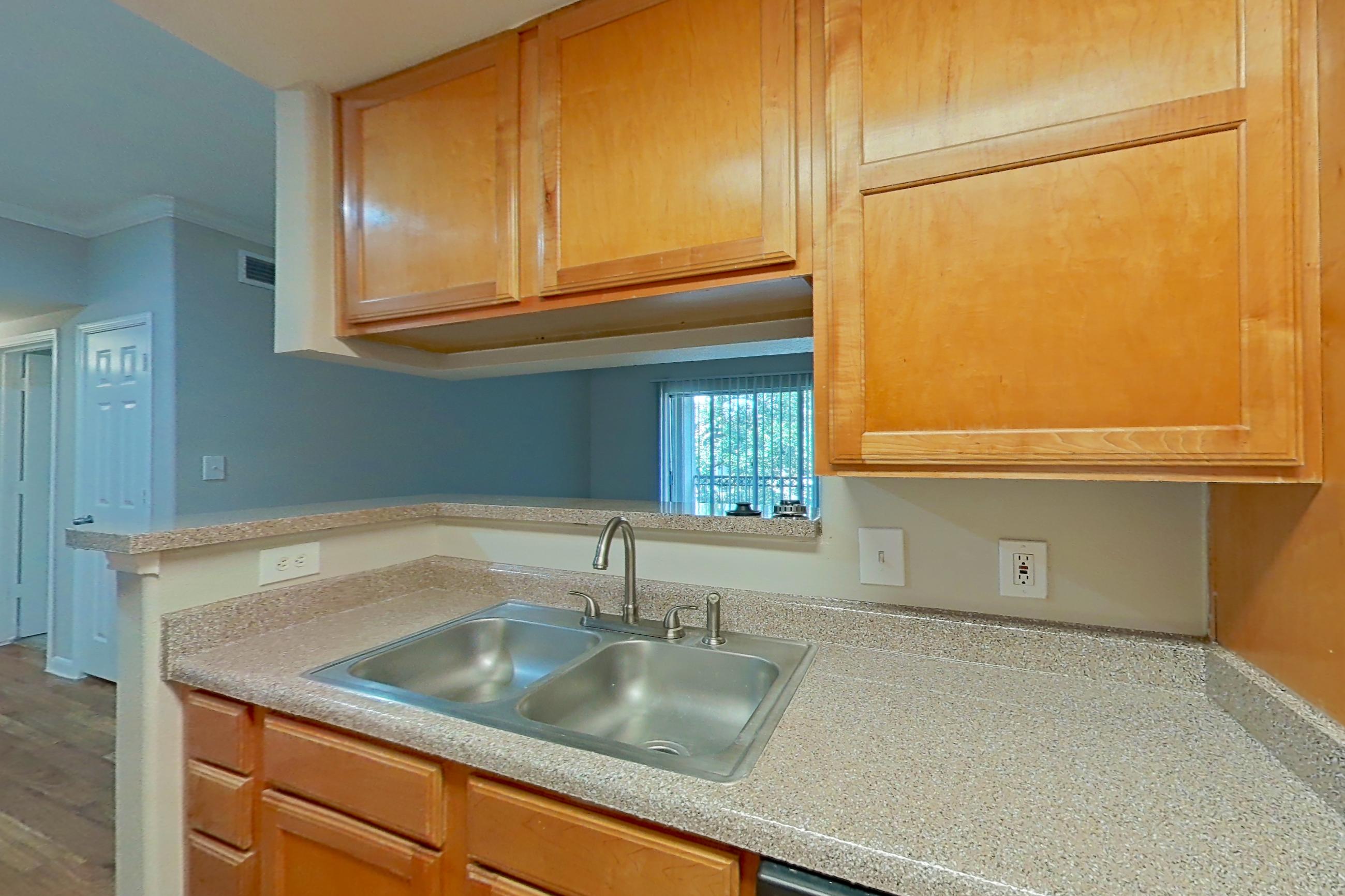 Kitchen with black appliances, dishwasher, electric range, light countertops, light wood-finish flooring, microwave, refrigerator, and white appliances, Apartment 1334 at Marquis on Westheimer