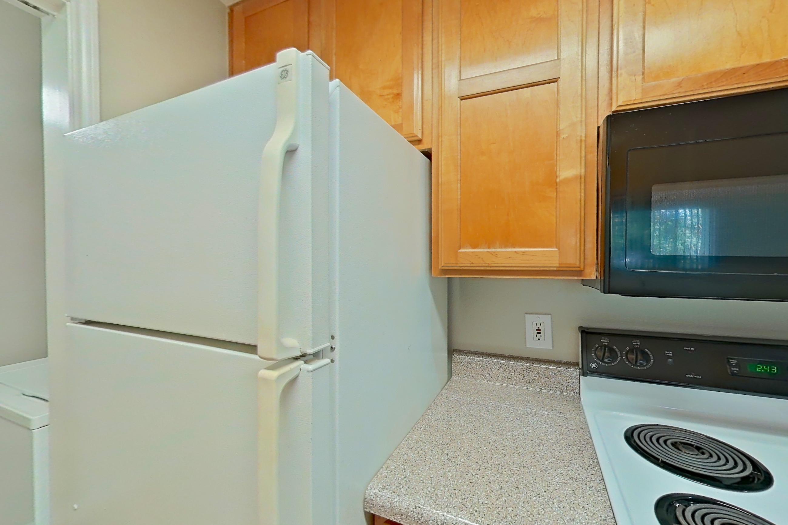 Kitchen with black appliances, dishwasher, electric range, light countertops, light wood-finish flooring, microwave, refrigerator, and white appliances, Apartment 1334 at Marquis on Westheimer