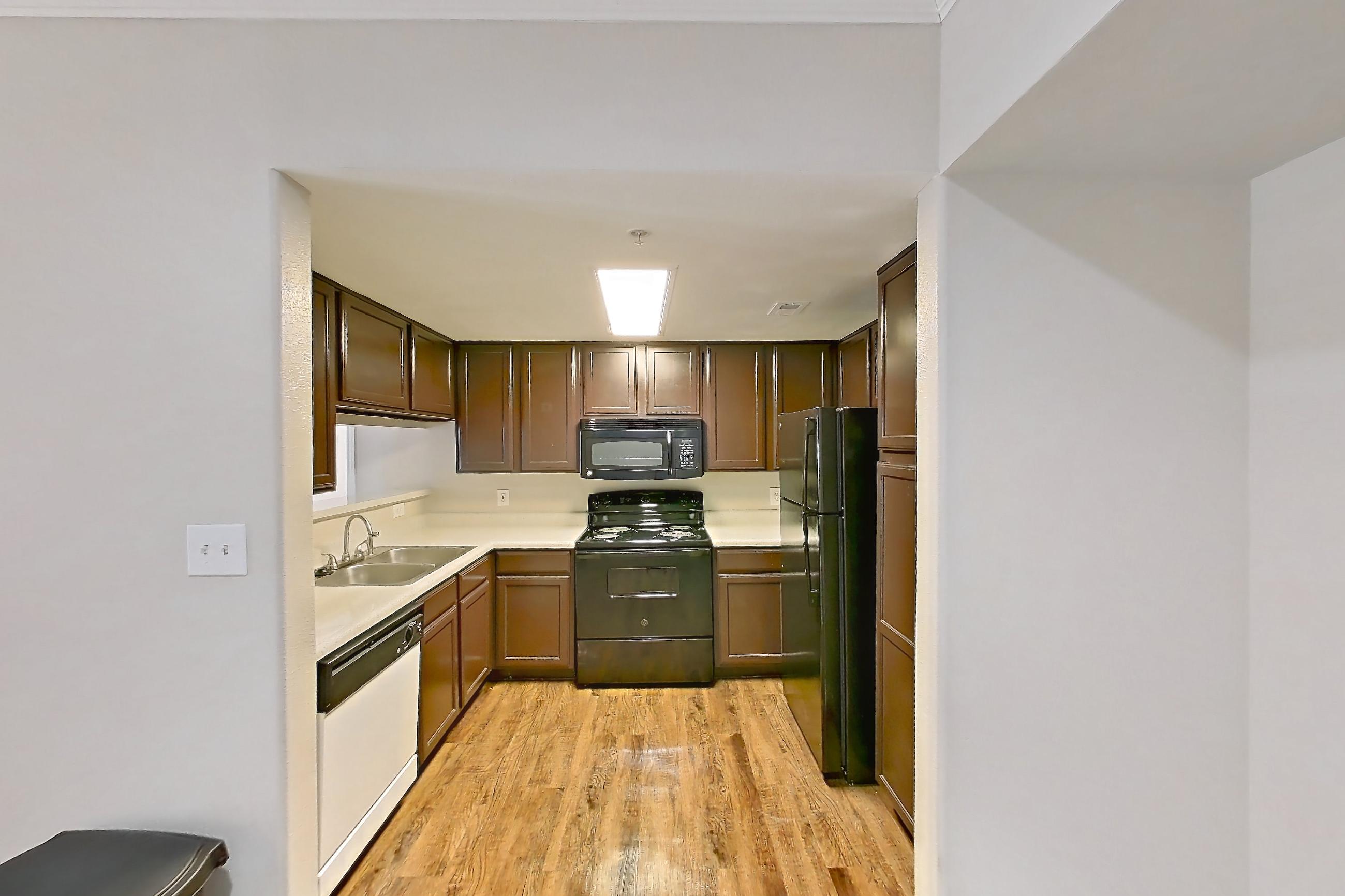 Dining room with black appliances, dark wood-finish flooring, dishwasher, electric range, light countertops, light wood-finish flooring, oven/range, refrigerator, and white appliances, Apartment 1437 at Marquis on Westheimer
