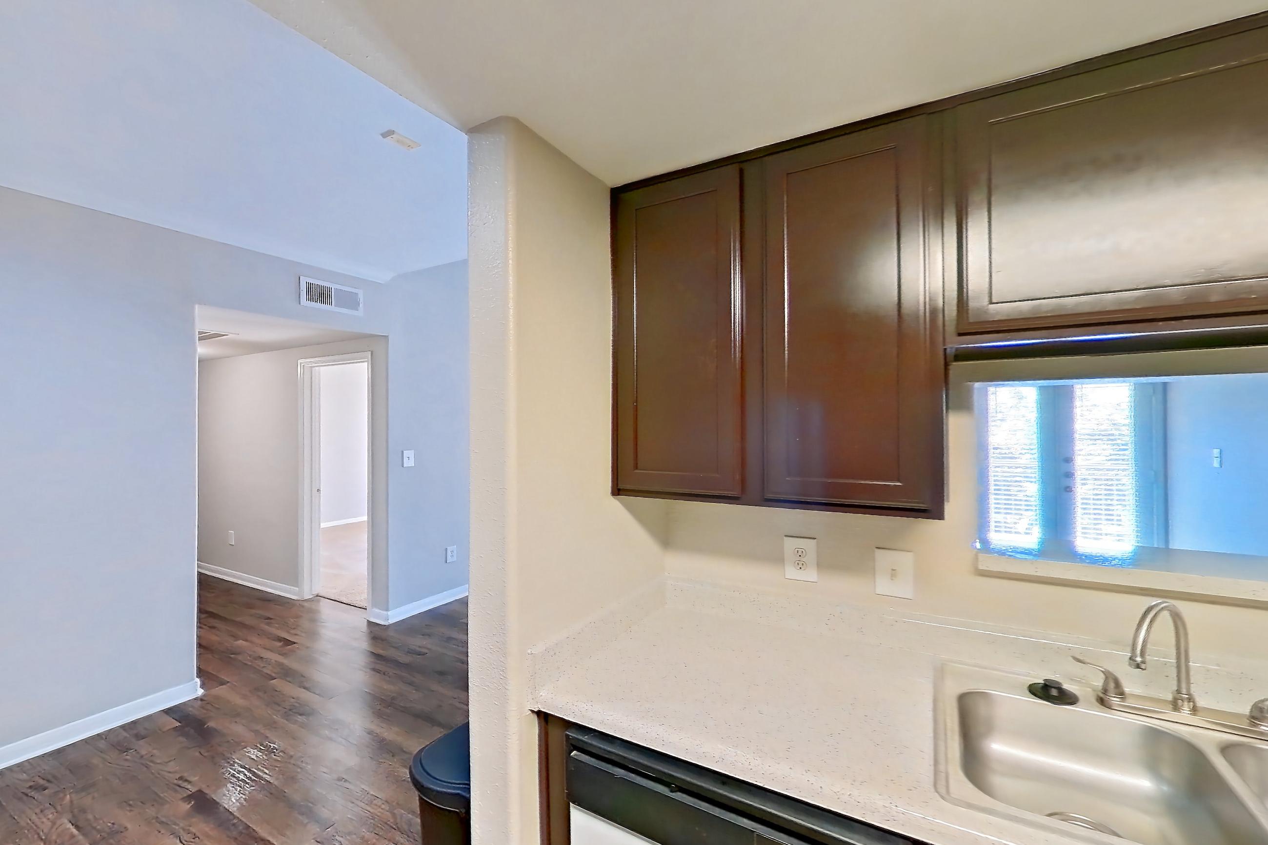 Kitchen with black appliances, dishwasher, electric range, glass shower door, light countertops, light stone countertops, light wood-finish flooring, microwave, oven/range, refrigerator, stall shower, walk-in shower, and white appliances, Apartment 1437 at Marquis on Westheimer