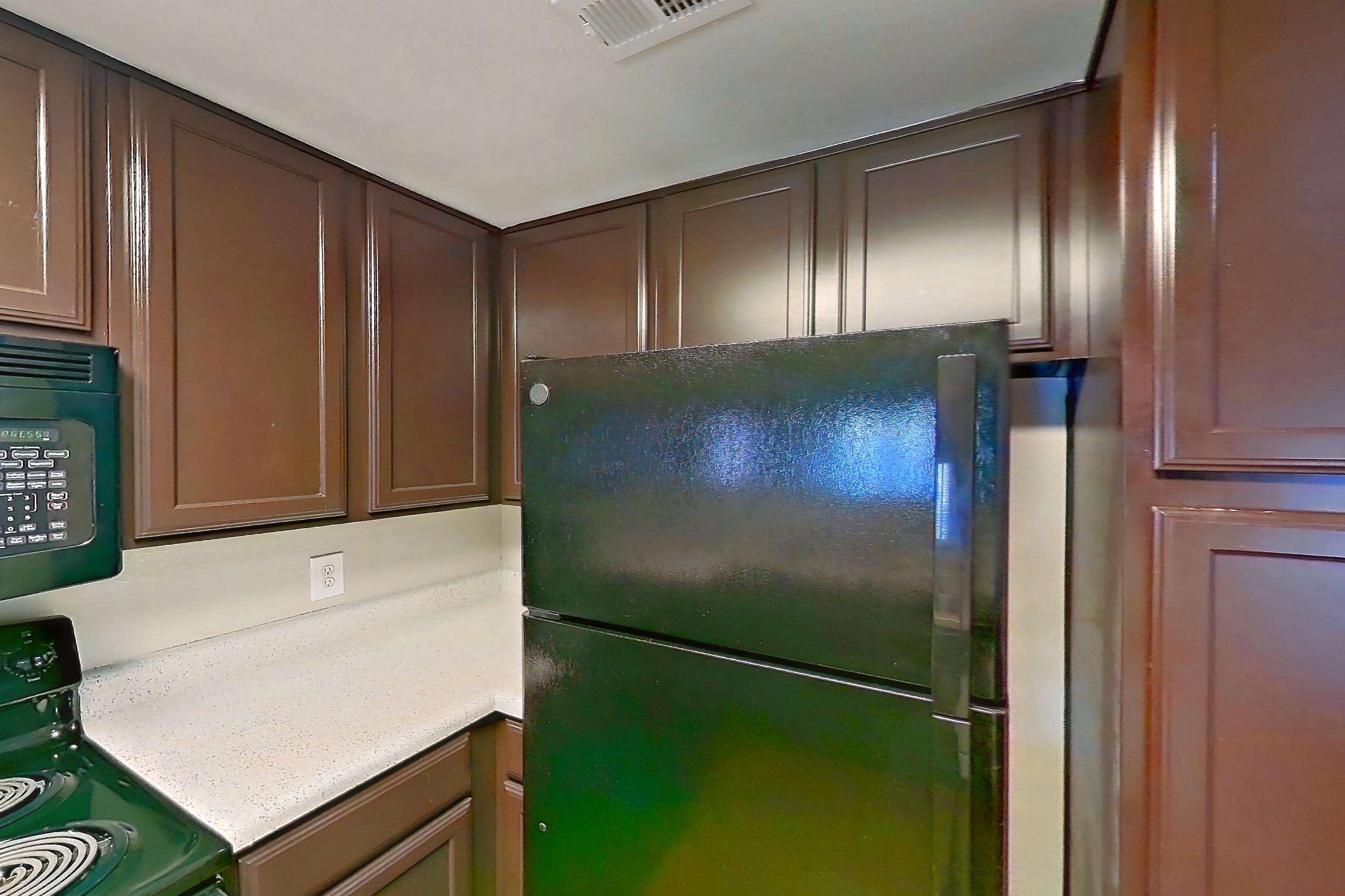 Kitchen with black appliances, dishwasher, electric range, glass shower door, light countertops, light stone countertops, light wood-finish flooring, microwave, oven/range, refrigerator, stall shower, walk-in shower, and white appliances, Apartment 1437 at Marquis on Westheimer