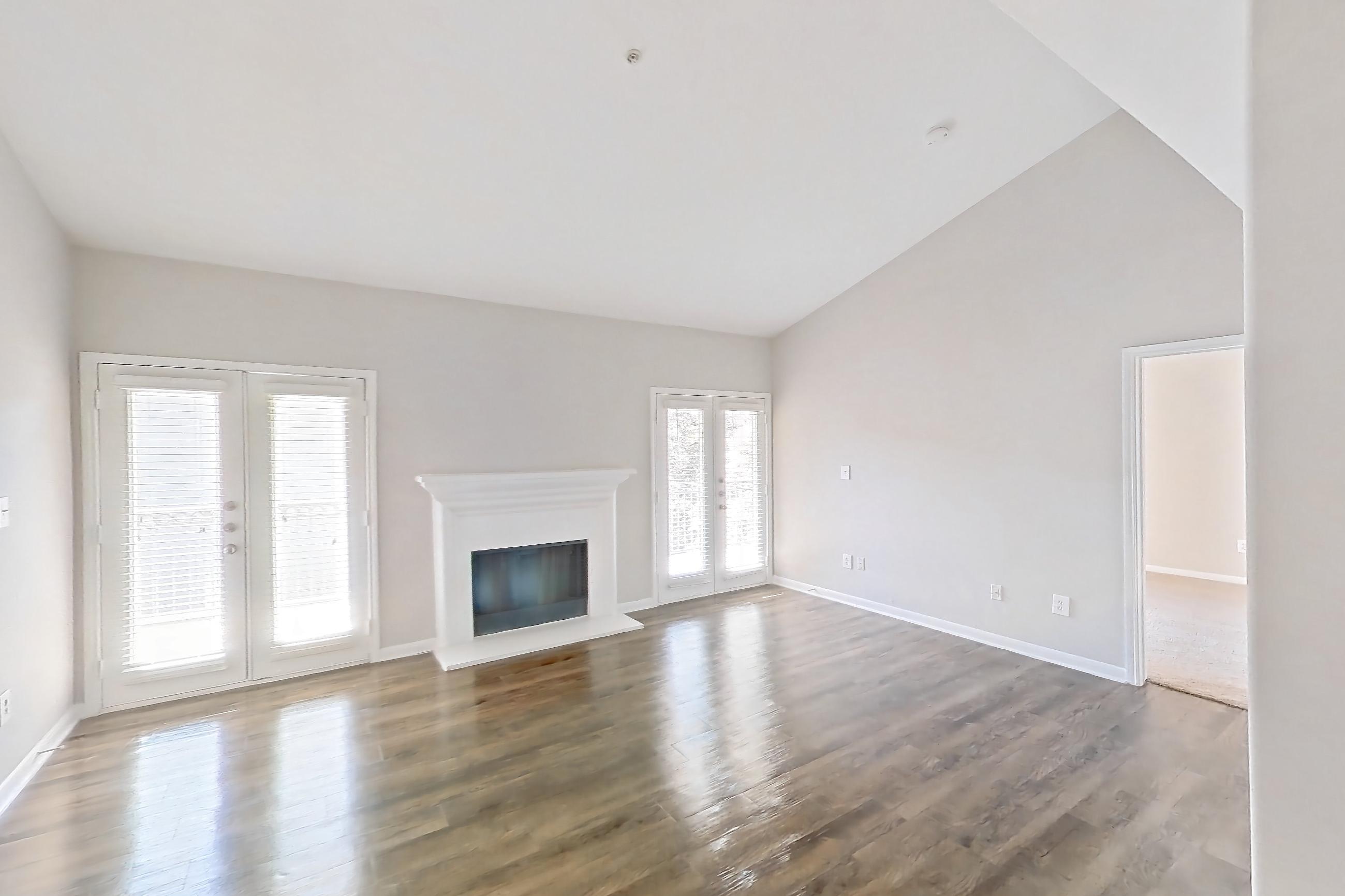 Living space with dark wood-finish flooring, fireplace, light countertops, light wood-finish flooring, refrigerator, and stainless steel appliances, Apartment 1437 at Marquis on Westheimer