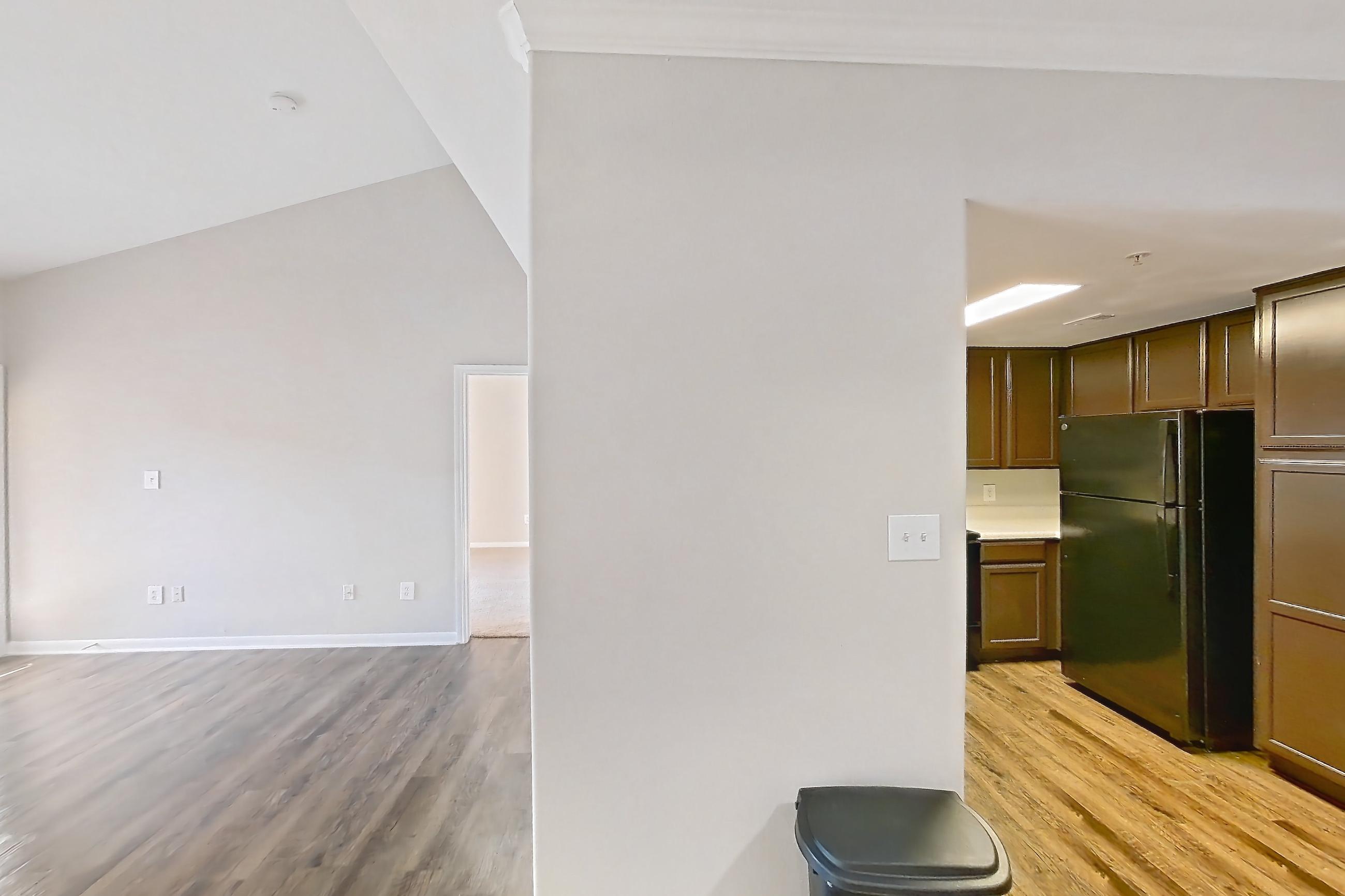 Living space with dark wood-finish flooring, fireplace, light countertops, light wood-finish flooring, refrigerator, and stainless steel appliances, Apartment 1437 at Marquis on Westheimer