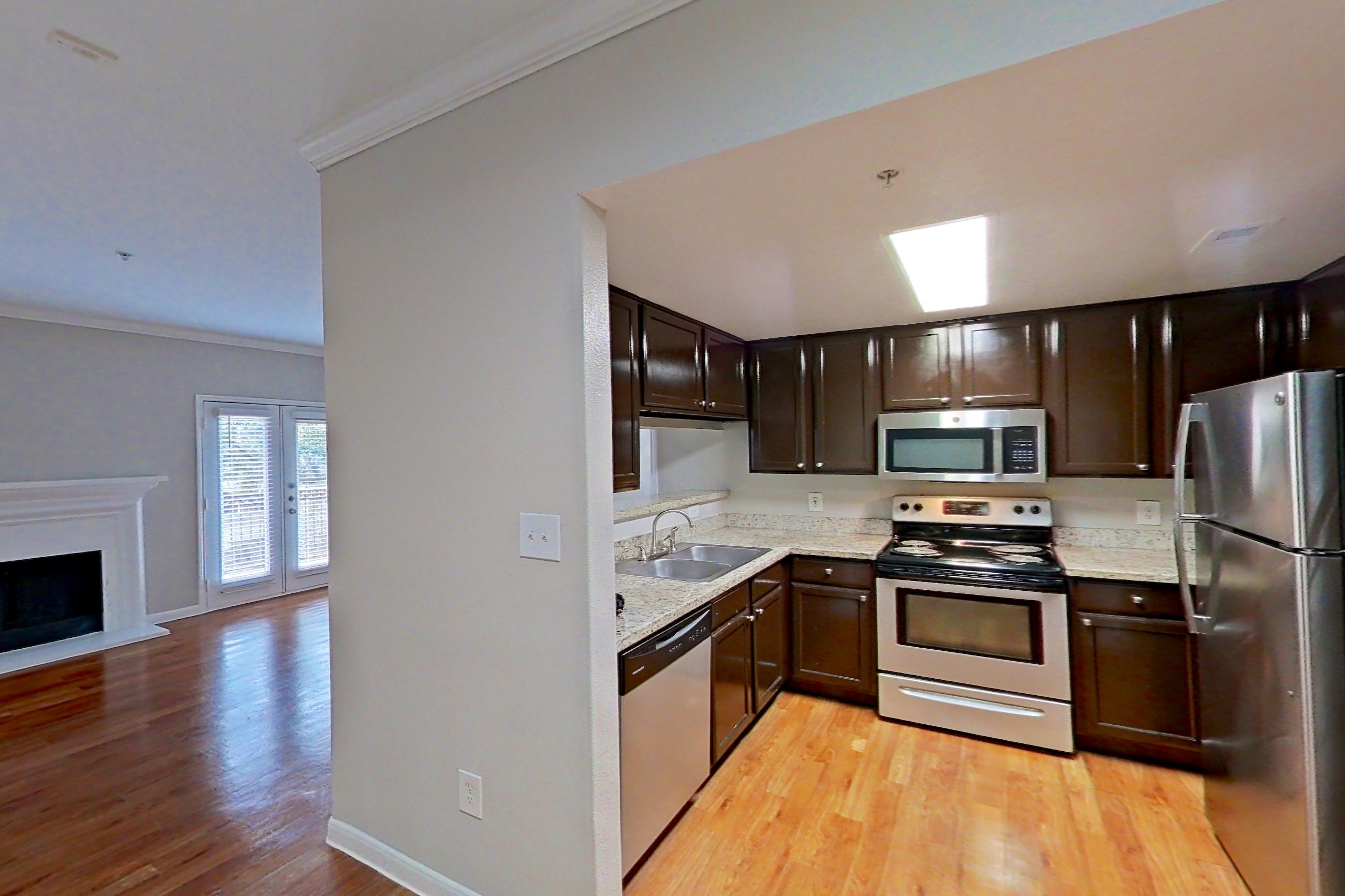 Dining area with dishwasher, electric range, fireplace, light stone countertops, light wood-finish flooring, oven/range, refrigerator, and stainless steel appliances, Apartment 1427 at Marquis on Westheimer