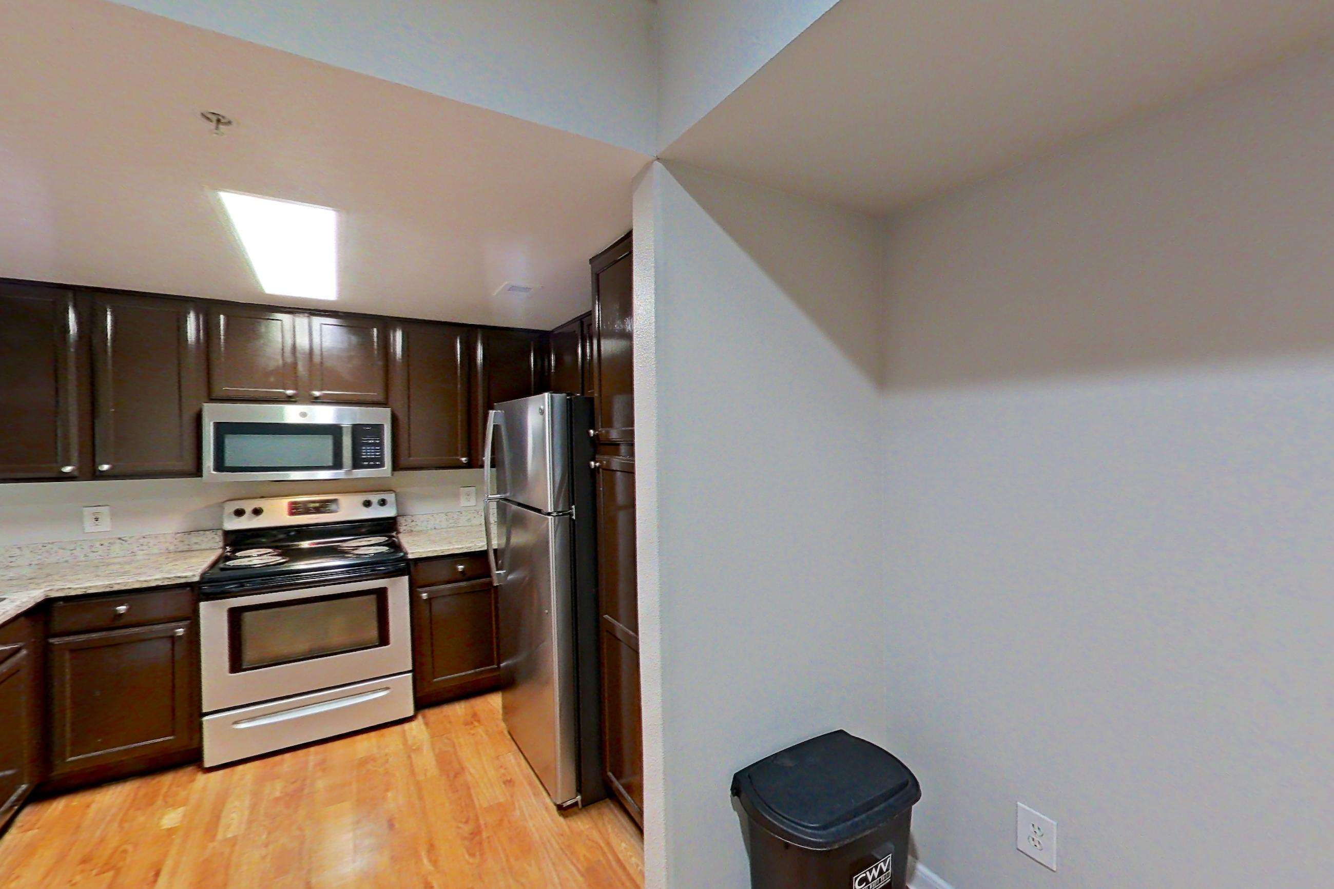 Dining area with dishwasher, electric range, fireplace, light stone countertops, light wood-finish flooring, oven/range, refrigerator, and stainless steel appliances, Apartment 1427 at Marquis on Westheimer
