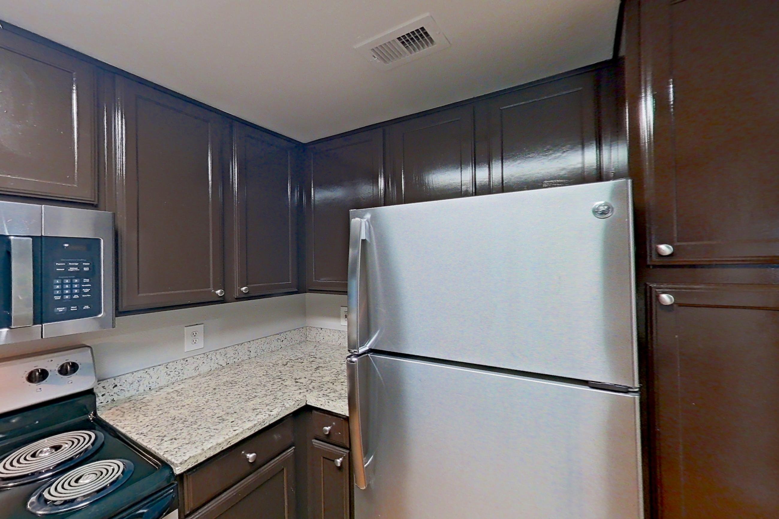 Kitchen with electric range, light stone countertops, light wood-finish flooring, microwave, oven/range, refrigerator, and stainless steel appliances, Apartment 1427 at Marquis on Westheimer