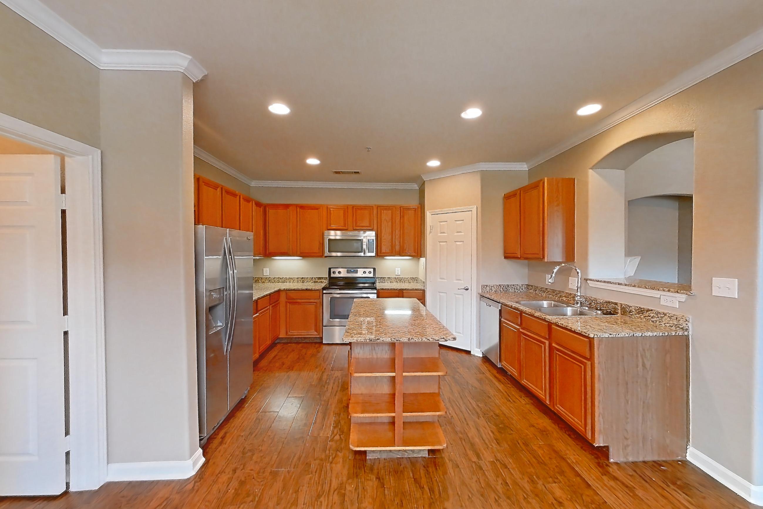 Dining room with dark wood-finish flooring, dishwasher, electric range, light countertops, light stone countertops, oven/range, refrigerator, stainless steel appliances, and water & ice dispenser, Apartment 1-0107 at Marquis at The Cascades I