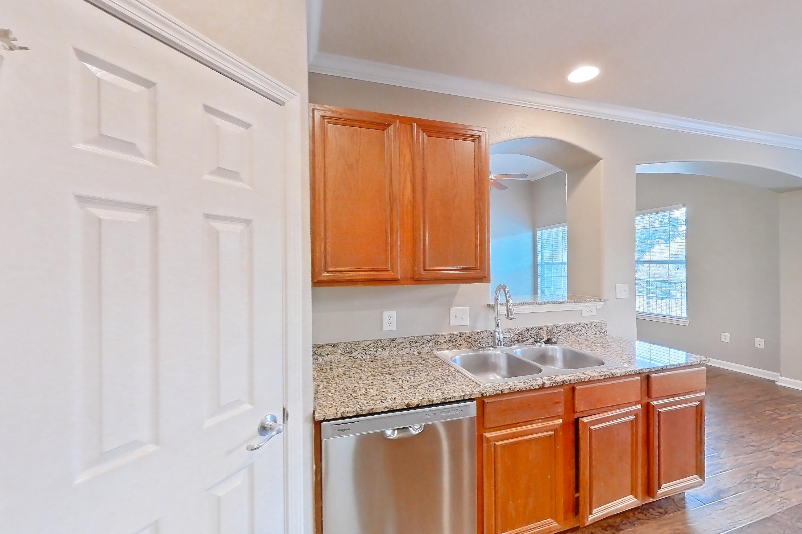 Kitchen with dark wood-finish flooring, dishwasher, electric range, light countertops, light stone countertops, light wood-finish flooring, oven/range, refrigerator, stainless steel appliances, water & ice dispenser, and wood-finish flooring, Apartment 1-0107 at Marquis at The Cascades I
