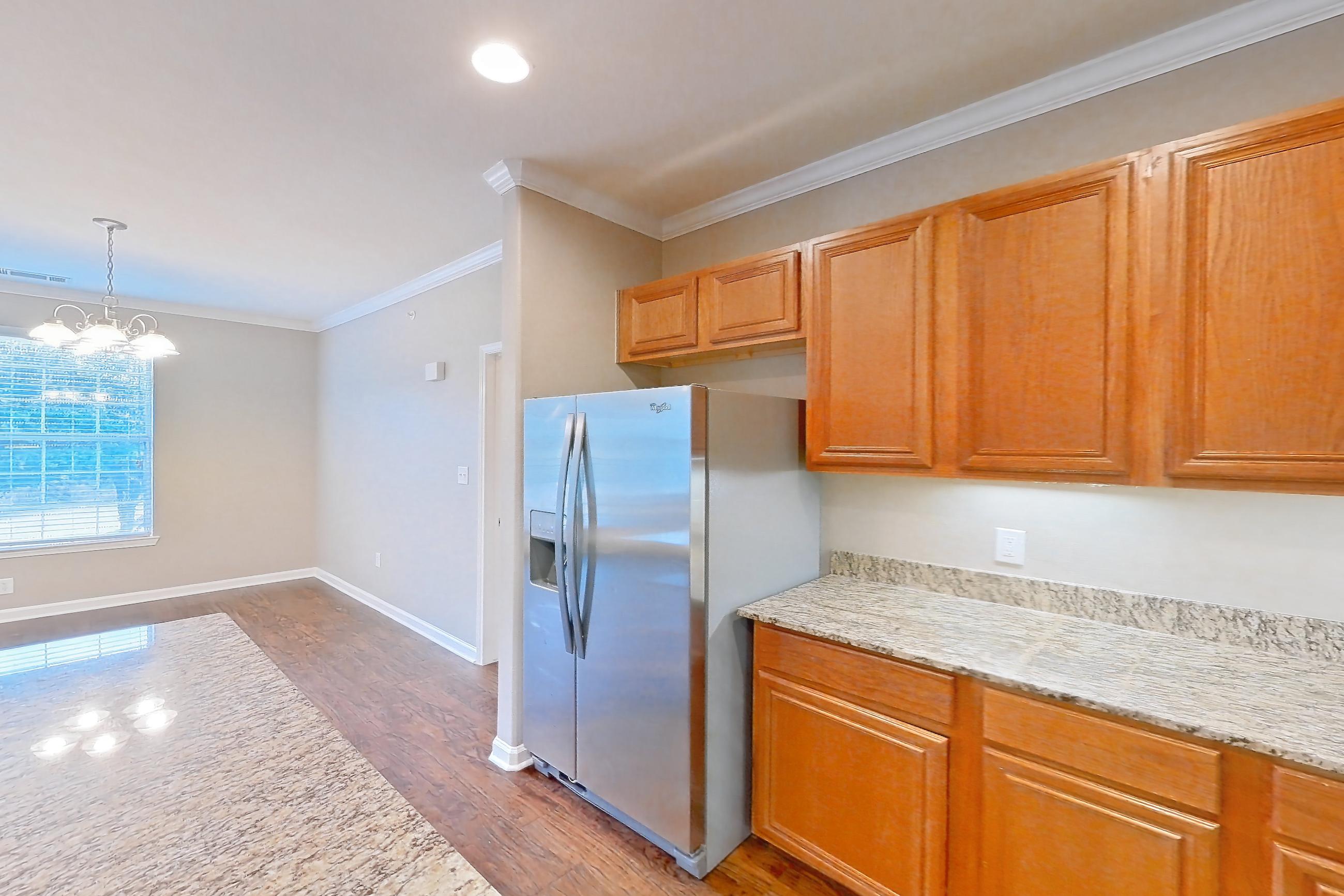 Kitchen with dark wood-finish flooring, dishwasher, electric range, light countertops, light stone countertops, light wood-finish flooring, oven/range, refrigerator, stainless steel appliances, water & ice dispenser, and wood-finish flooring, Apartment 1-0107 at Marquis at The Cascades I