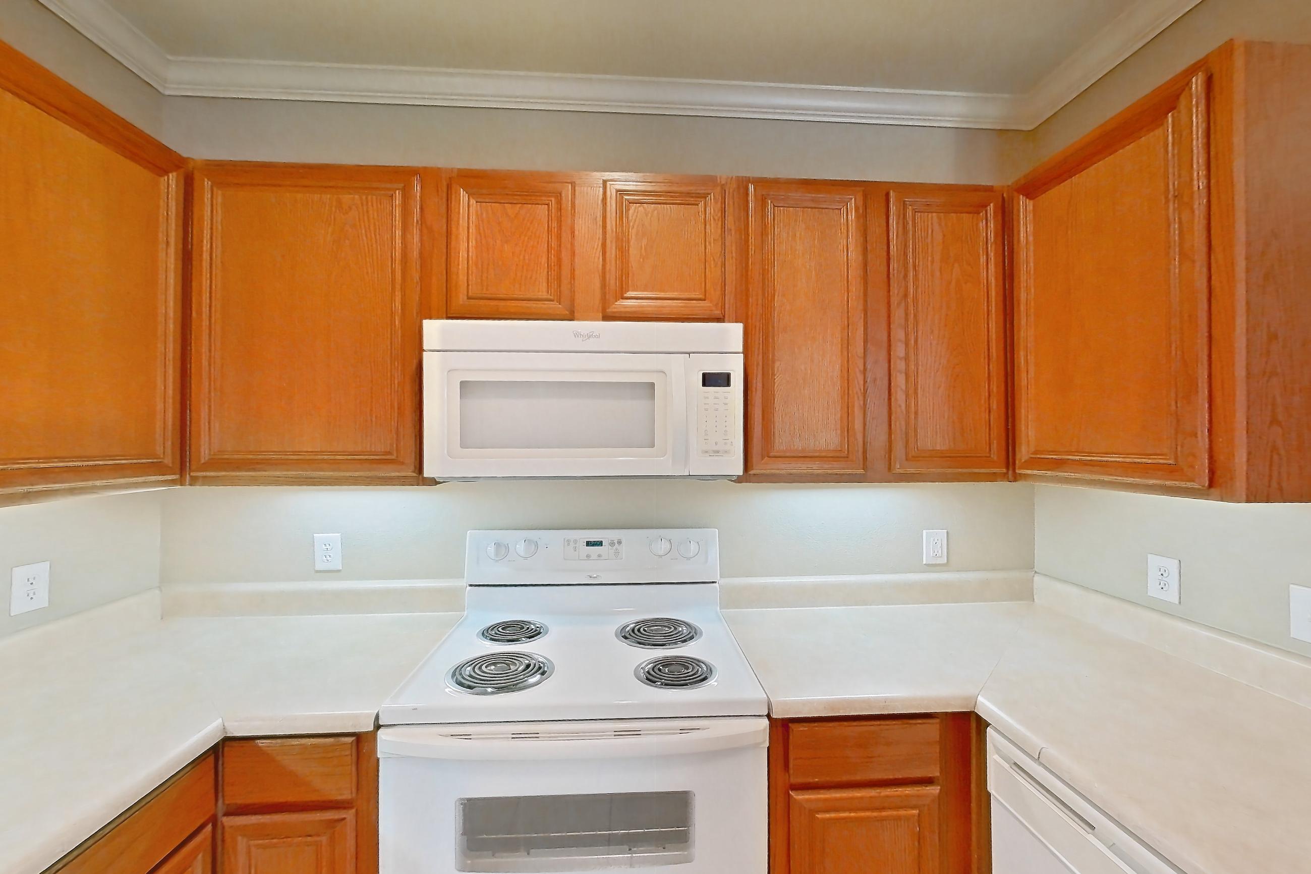 Kitchen with dishwasher, fireplace, light countertops, light tile flooring, light wood-finish flooring, refrigerator, tile fireplace, and white appliances, Apartment 1-0603 at Marquis at The Cascades I