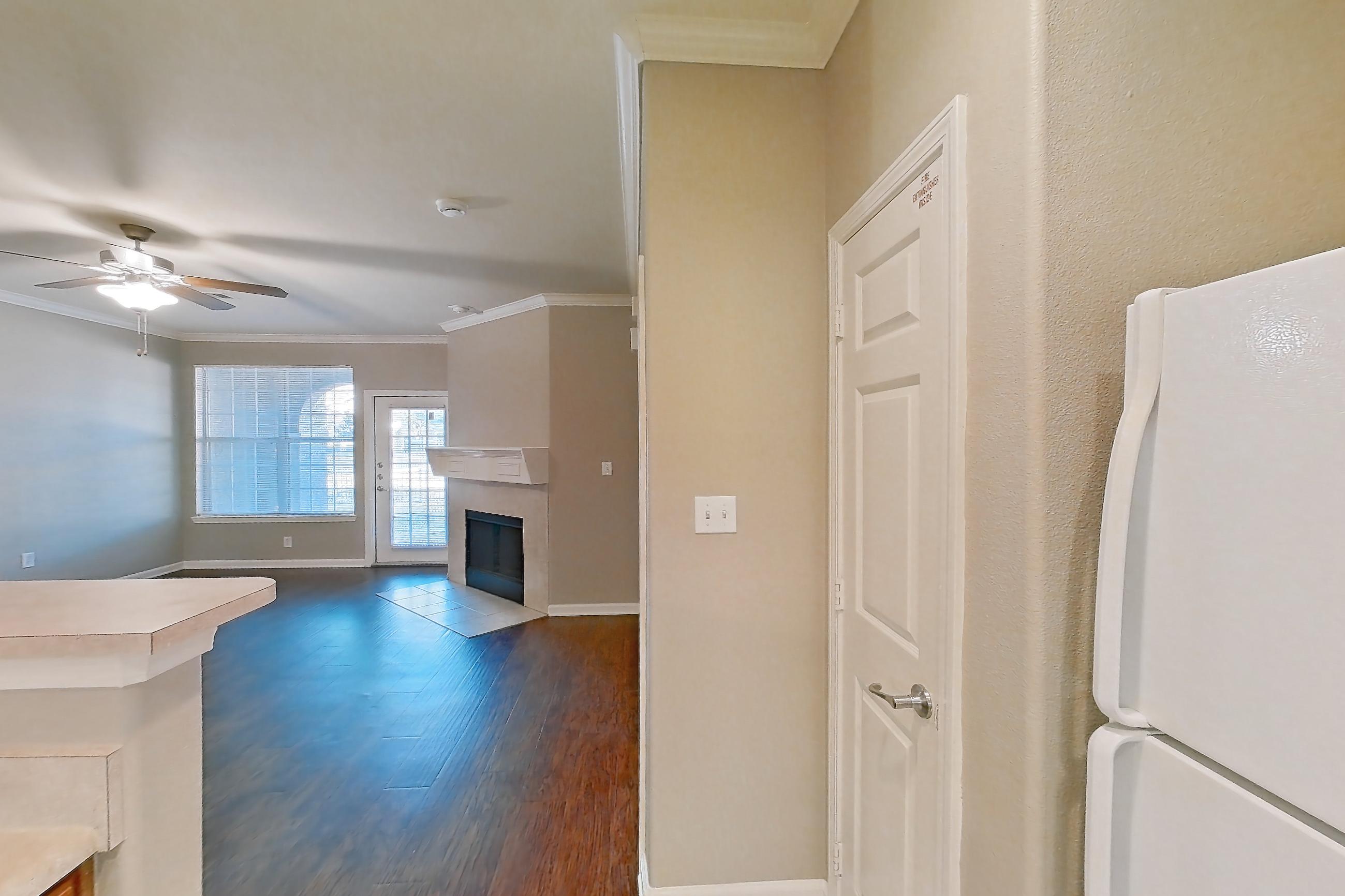 Kitchen with dishwasher, fireplace, light countertops, light tile flooring, light wood-finish flooring, refrigerator, tile fireplace, and white appliances, Apartment 1-0603 at Marquis at The Cascades I