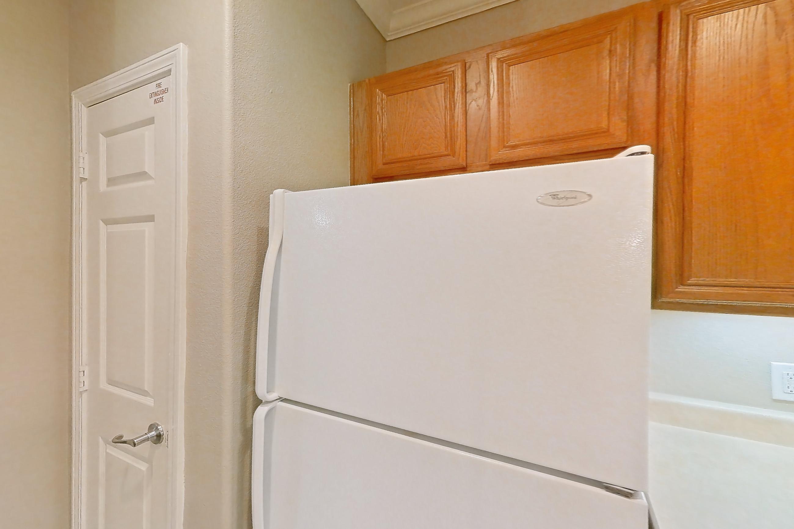 Kitchen with dishwasher, fireplace, light countertops, light tile flooring, light wood-finish flooring, refrigerator, tile fireplace, and white appliances, Apartment 1-0603 at Marquis at The Cascades I