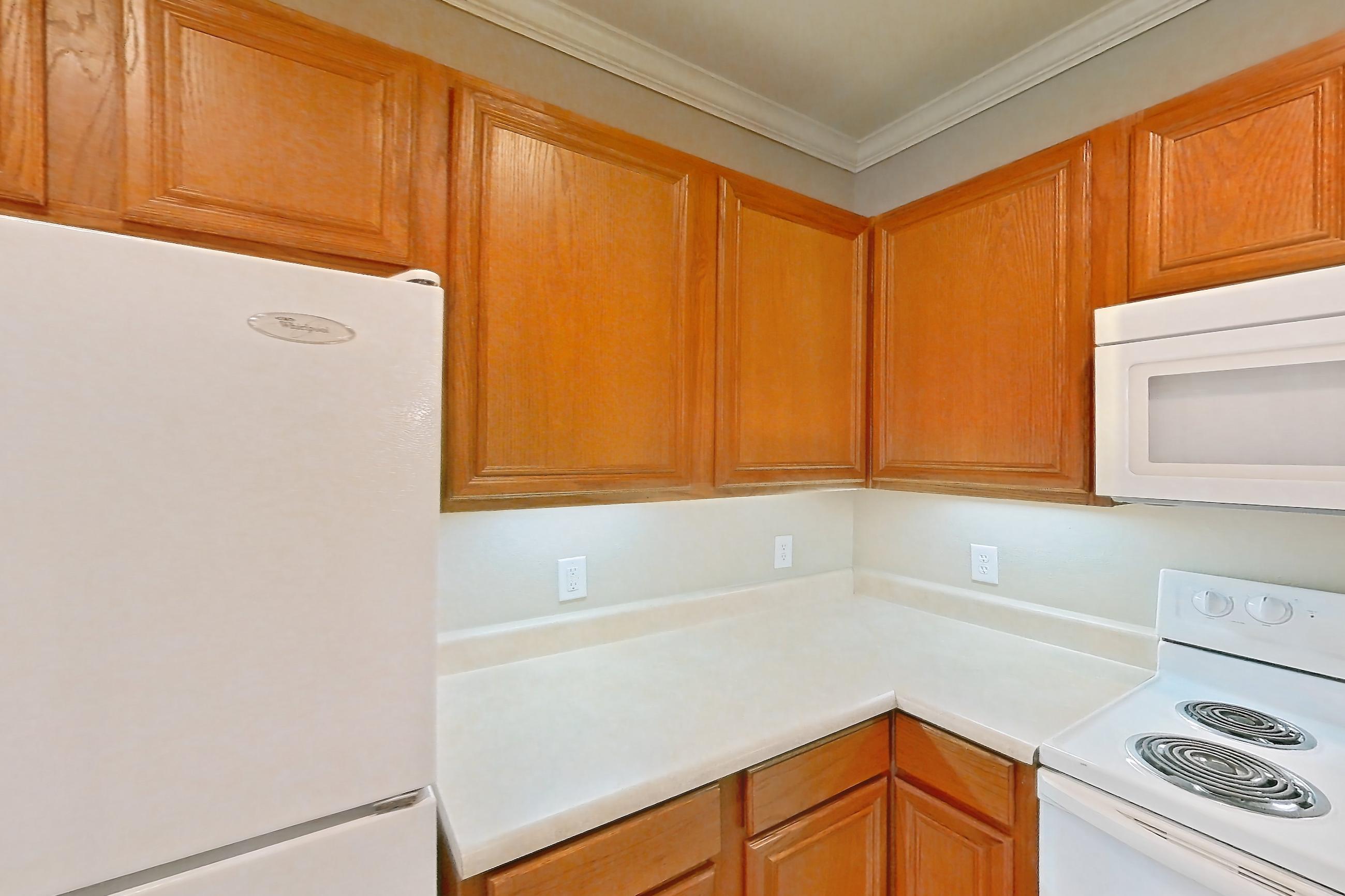 Kitchen with dishwasher, fireplace, light countertops, light tile flooring, light wood-finish flooring, refrigerator, tile fireplace, and white appliances, Apartment 1-0603 at Marquis at The Cascades I