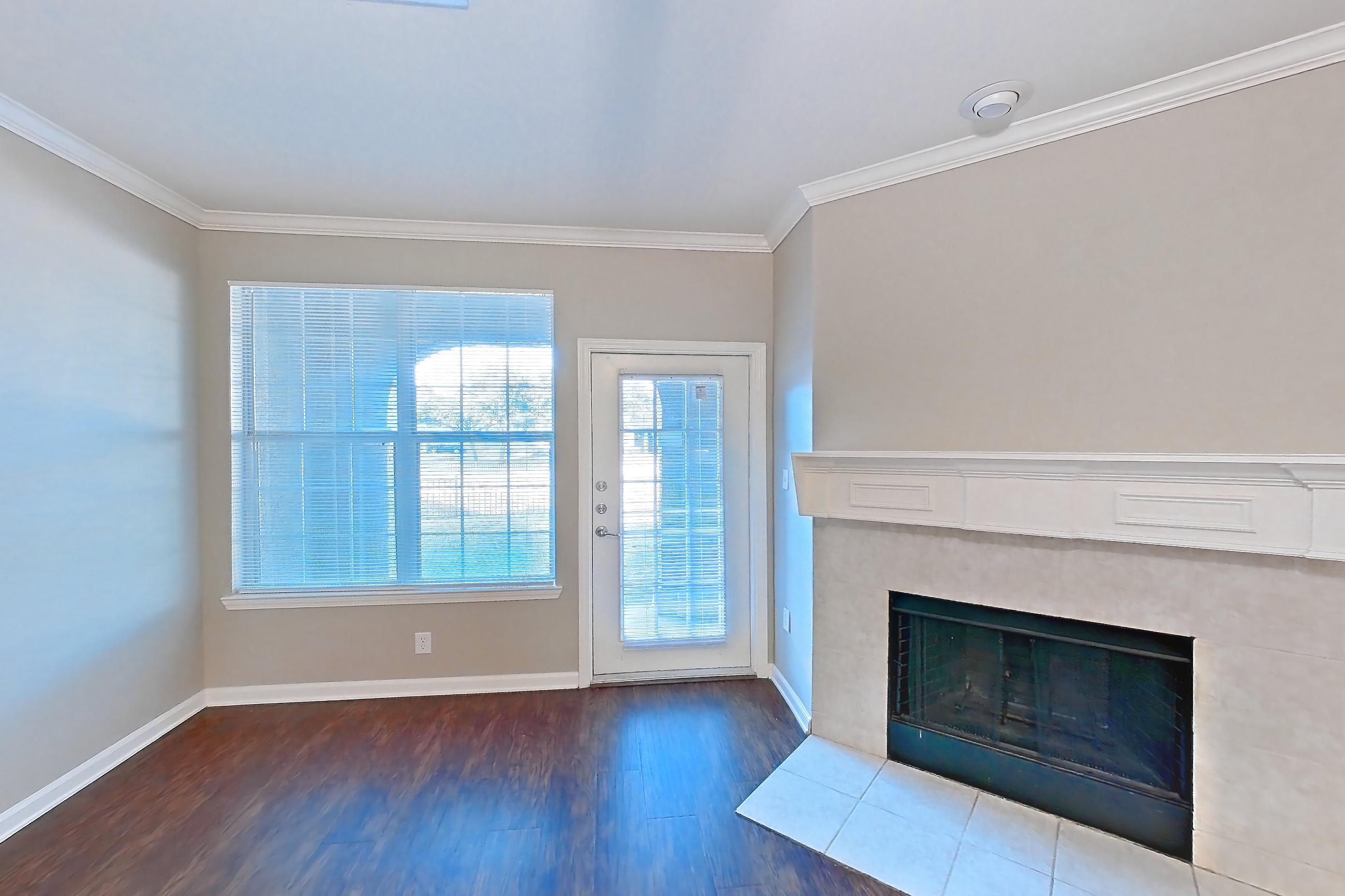 Living room with dark tile flooring, dark wood-finish flooring, fireplace, light tile flooring, light wood-finish flooring, marble fireplace, refrigerator, tile fireplace, and white appliances, Apartment 1-0603 at Marquis at The Cascades I