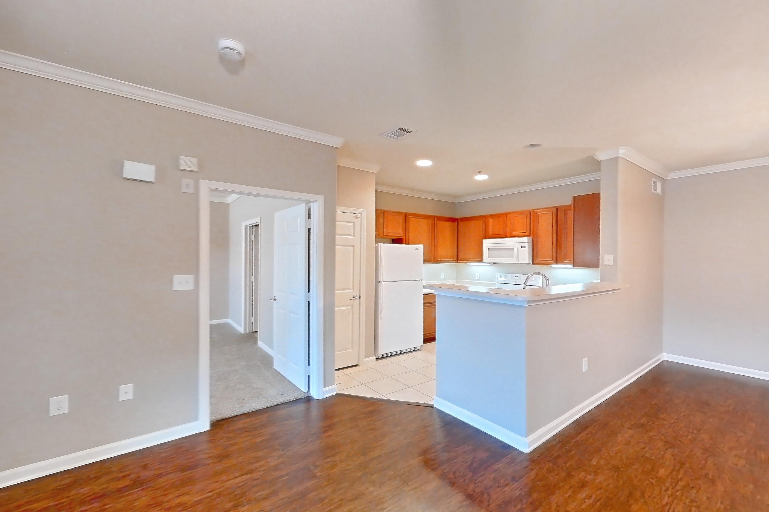 Living room with dark tile flooring, dark wood-finish flooring, fireplace, light tile flooring, light wood-finish flooring, marble fireplace, refrigerator, tile fireplace, and white appliances, Apartment 1-0603 at Marquis at The Cascades I