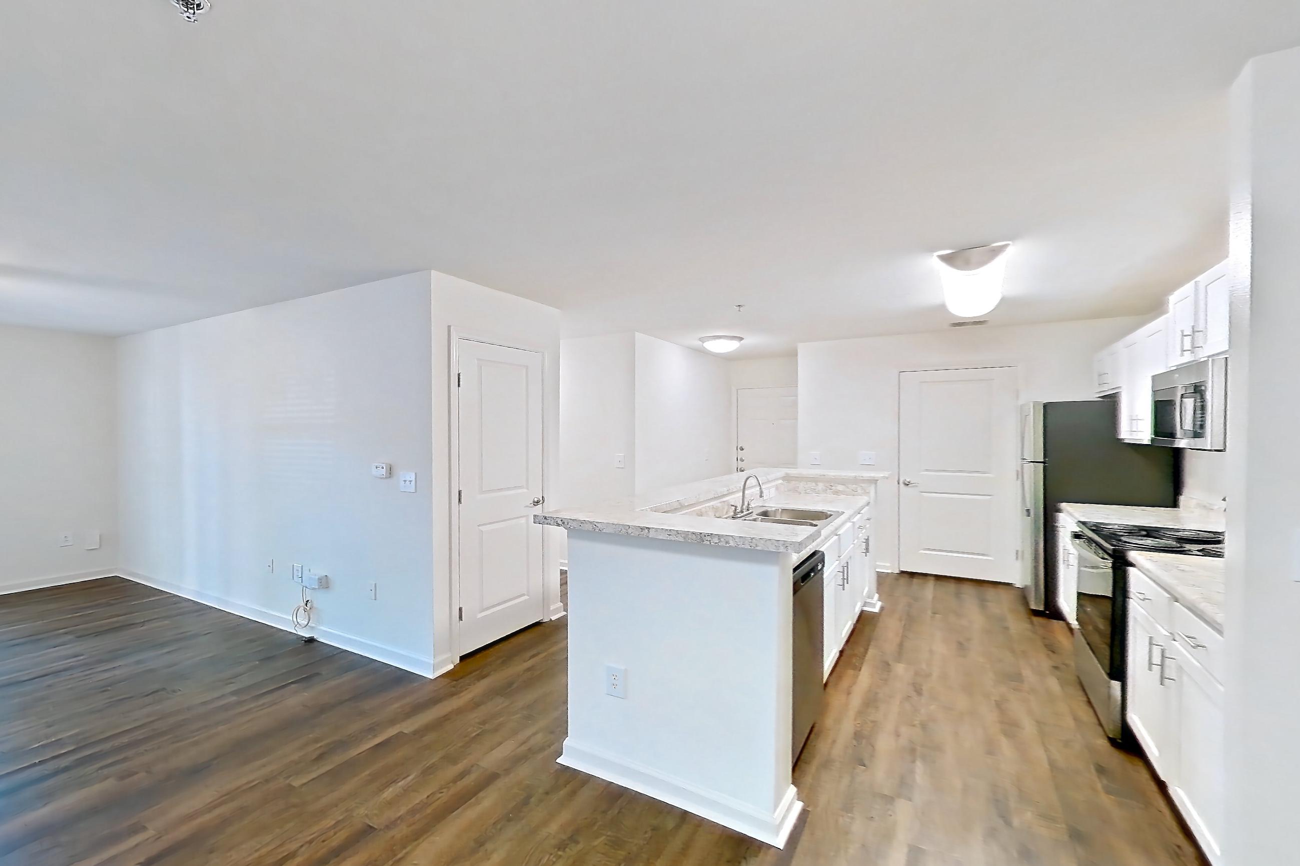 Dining room with dark wood-finish flooring, dishwasher, kitchen island, light countertops, oven/range, and stainless steel appliances, Apartment 09-1016 at Marquis on Cary Parkway