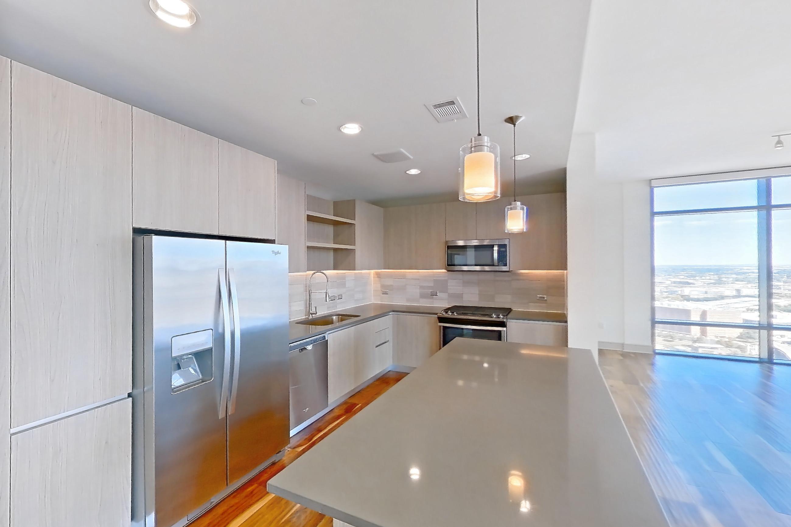 Kitchen space with dark countertops, dishwasher, light wood-finish flooring, oven/range, refrigerator, and stainless steel appliances, Apartment 2810 at Aris Market Square