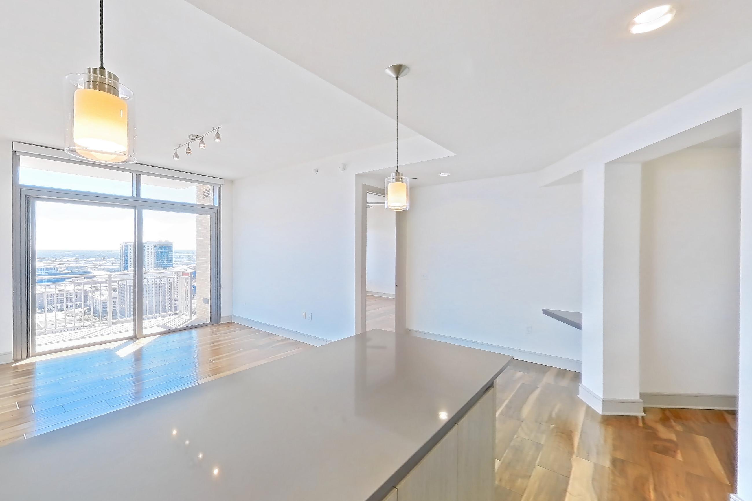 Kitchen with dark countertops, gas range, light countertops, light wood-finish flooring, oven/range, refrigerator, stainless steel appliances, and water & ice dispenser, Apartment 2810 at Aris Market Square