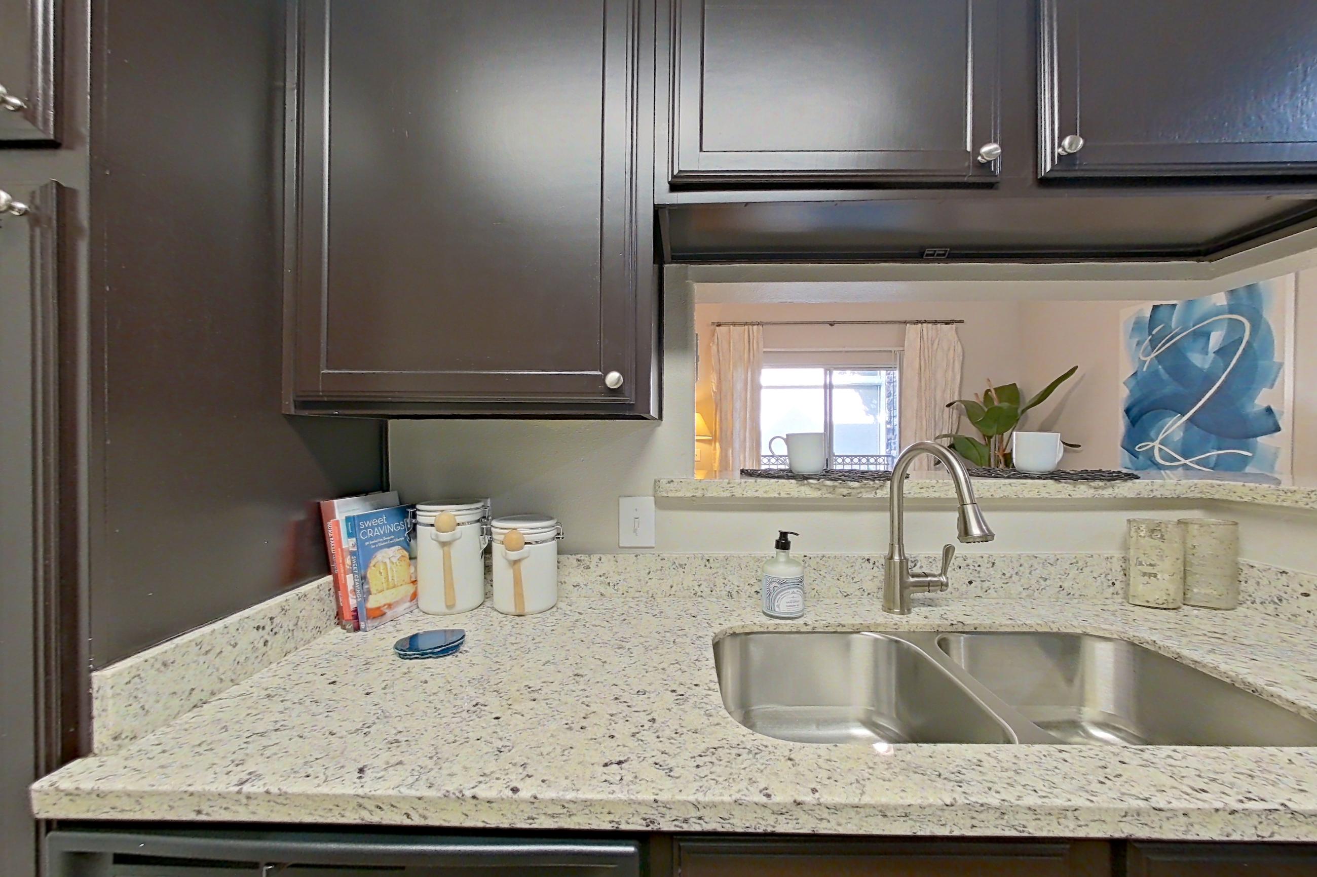 Kitchen with dishwasher, electric range, in-unit laundry, light stone countertops, light wood-finish flooring, refrigerator, and stainless steel appliances, Apartment 0115 at Marquis on Westheimer