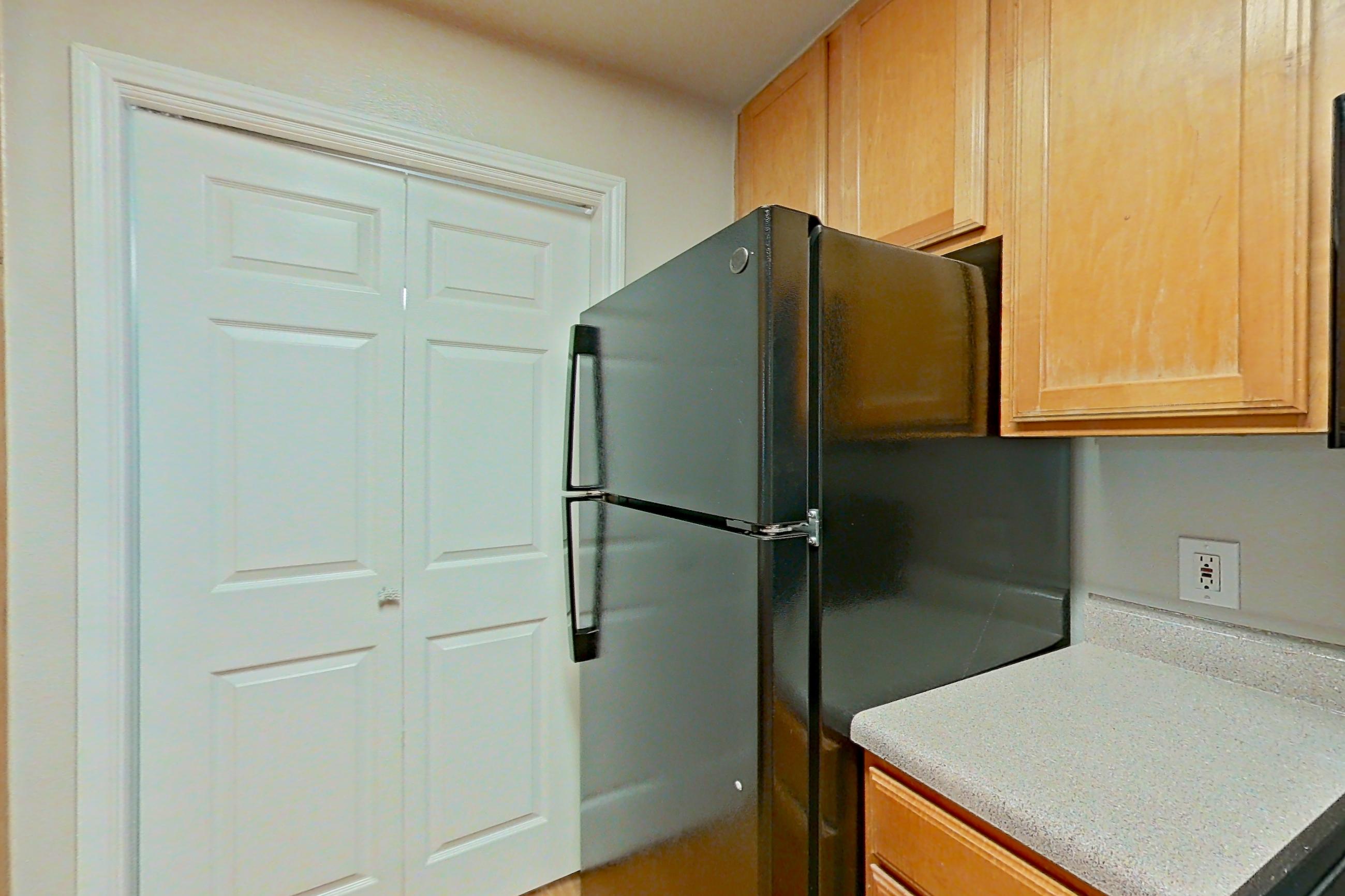 Kitchen with black appliances, electric range, light countertops, light wood-finish flooring, oven/range, and refrigerator, Apartment 0118 at Marquis on Westheimer