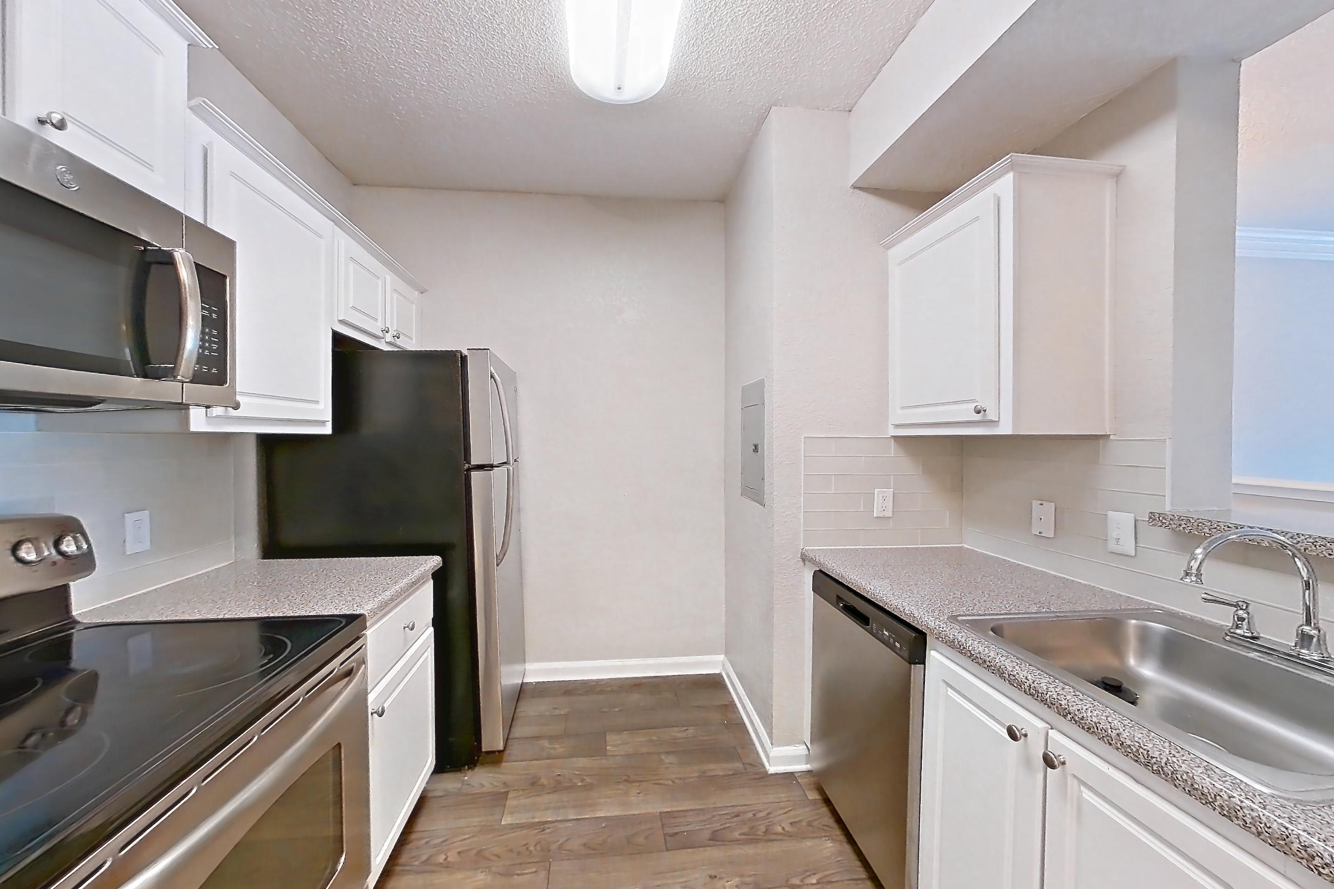 Kitchen with dishwasher, electric range, light countertops, light stone countertops, microwave, oven/range, refrigerator, and stainless steel appliances, Apartment 124 at Marquis Midtown West