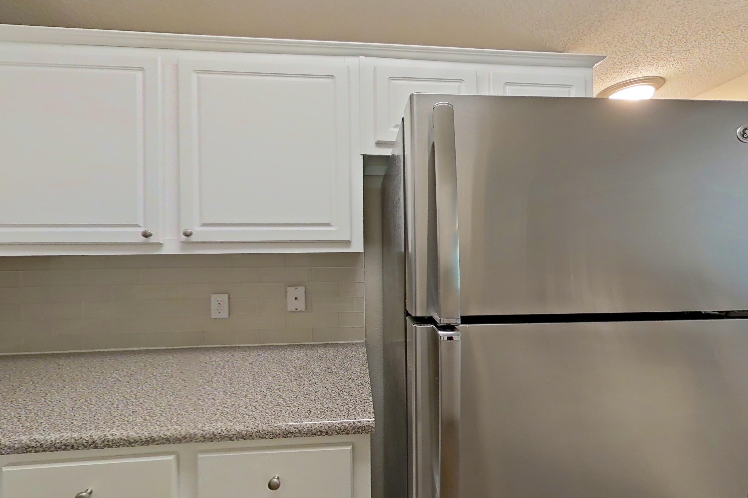 Kitchen with dark wood-finish flooring, dishwasher, electric range, light countertops, light stone countertops, microwave, oven/range, refrigerator, and stainless steel appliances, Apartment 434 at Marquis Midtown West