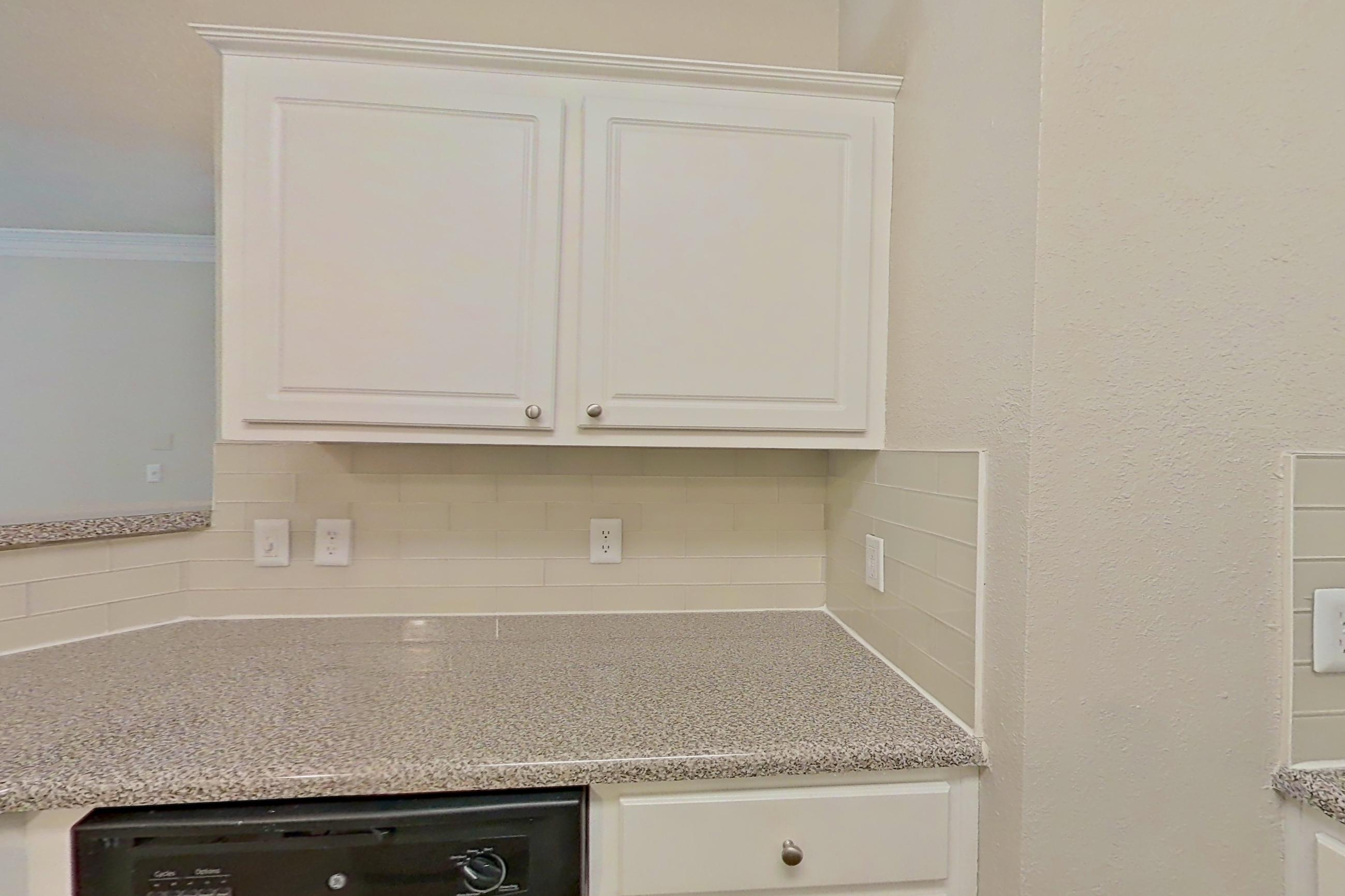 Kitchen with dark wood-finish flooring, dishwasher, electric range, light countertops, light stone countertops, microwave, oven/range, refrigerator, and stainless steel appliances, Apartment 434 at Marquis Midtown West