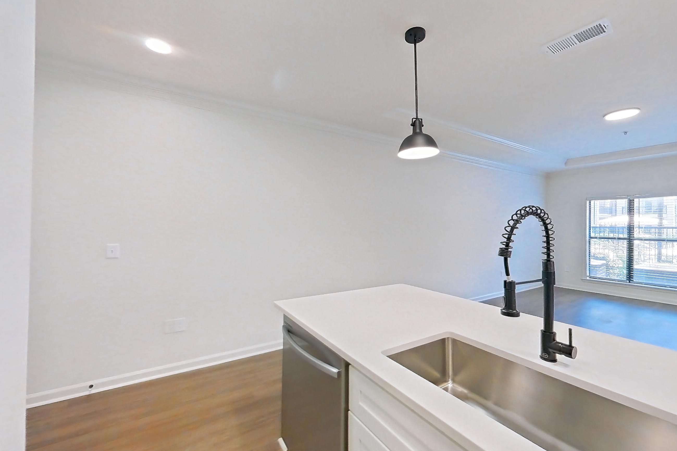 Kitchen with dishwasher, electric range, light countertops, light stone countertops, light wood-finish flooring, microwave, oven/range, refrigerator, and stainless steel appliances, Apartment 1110 at Cortland at Armour Yards