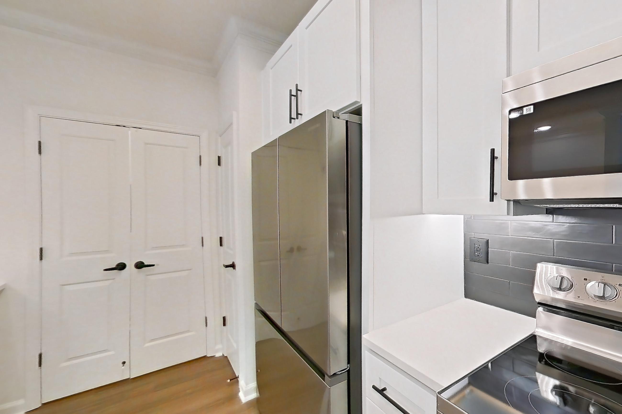 Kitchen with dishwasher, electric range, light countertops, light stone countertops, light wood-finish flooring, microwave, oven/range, refrigerator, and stainless steel appliances, Apartment 1110 at Cortland at Armour Yards