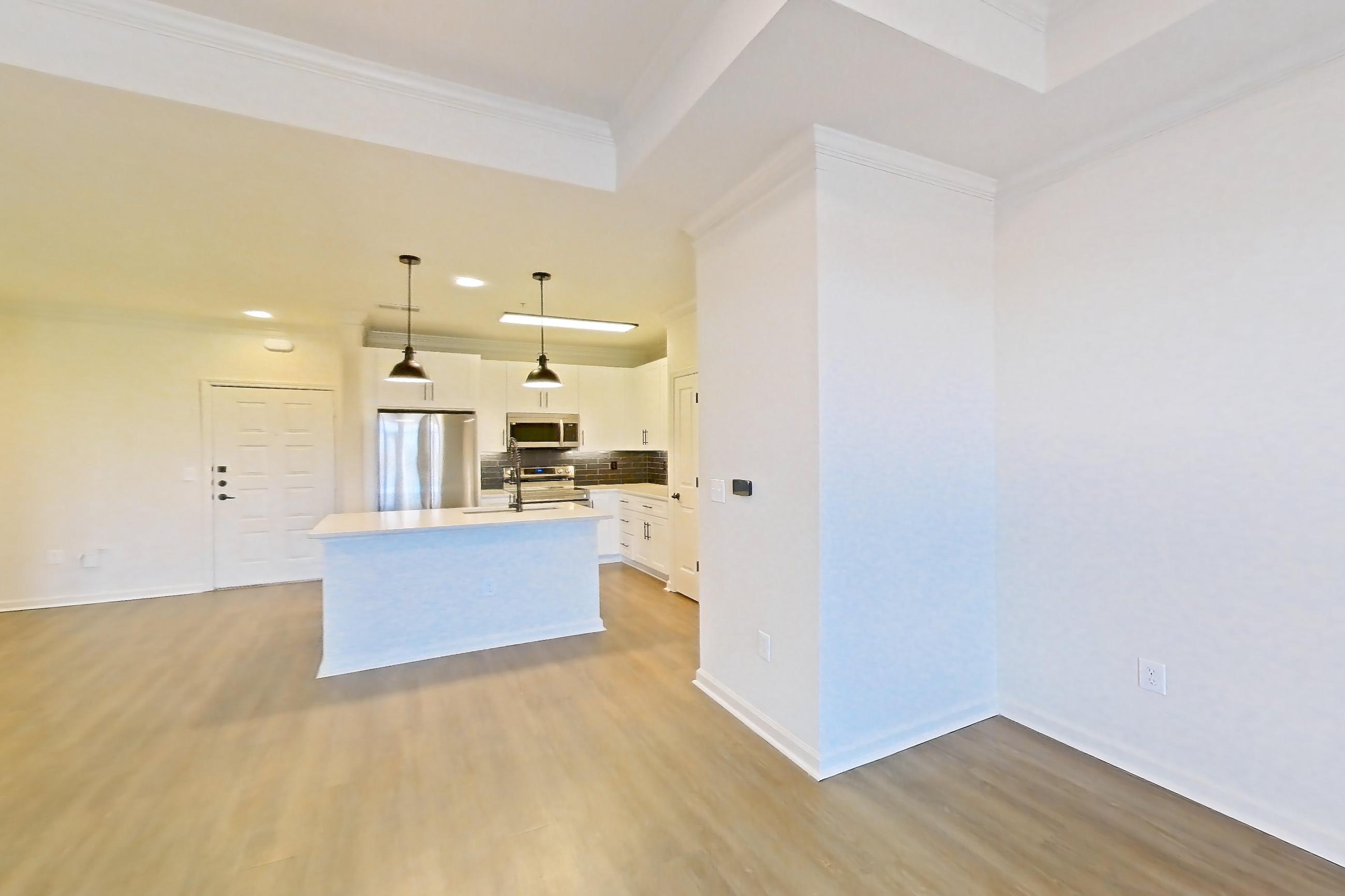 Living room with electric range, kitchen island, light countertops, light wood-finish flooring, oven/range, and stainless steel appliances, Apartment 1403 at Cortland at Armour Yards