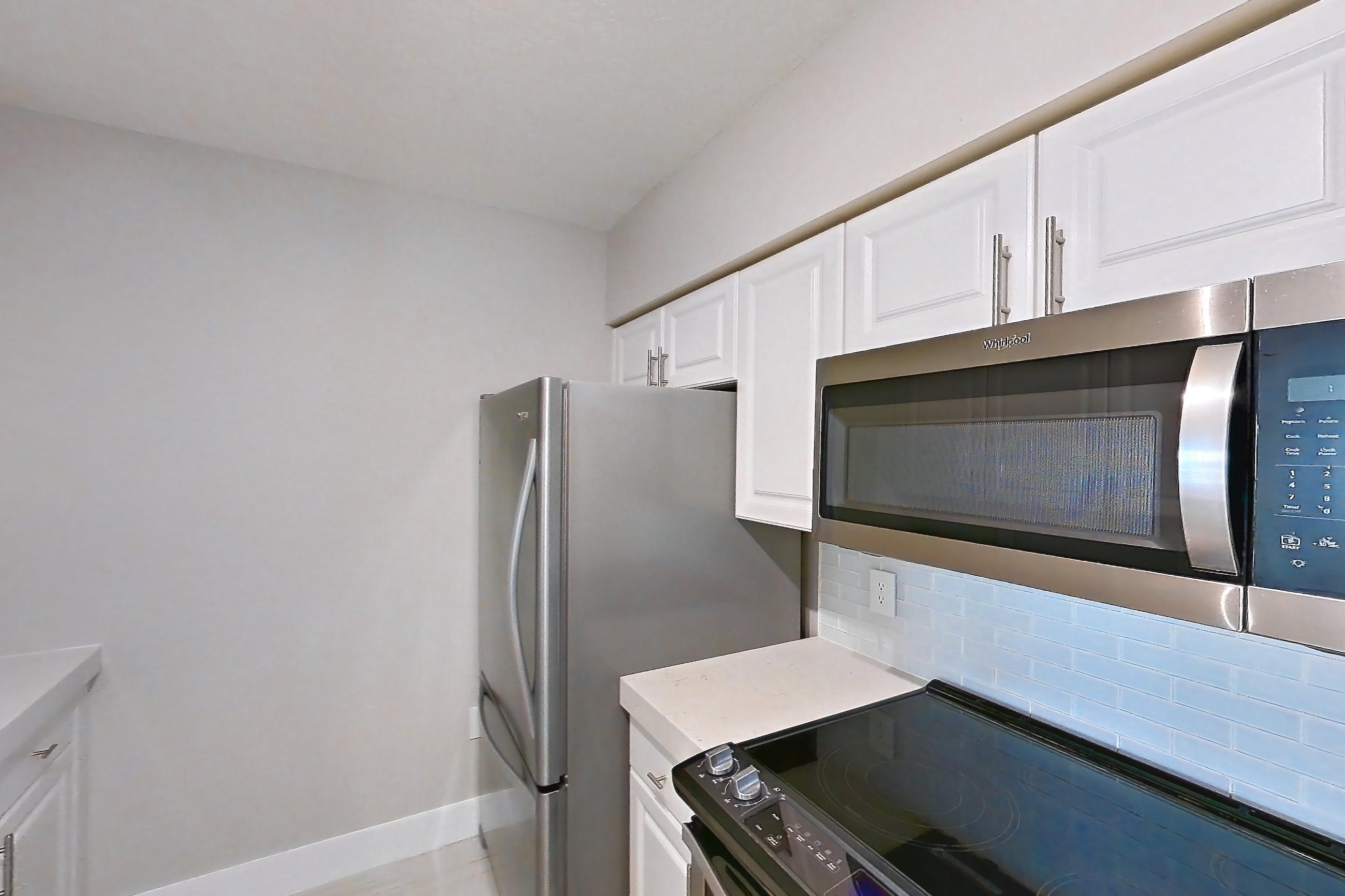 Kitchen with dishwasher, electric range, light countertops, light stone countertops, oven/range, refrigerator, and stainless steel appliances, Apartment 0952 at Sunrise Harbor