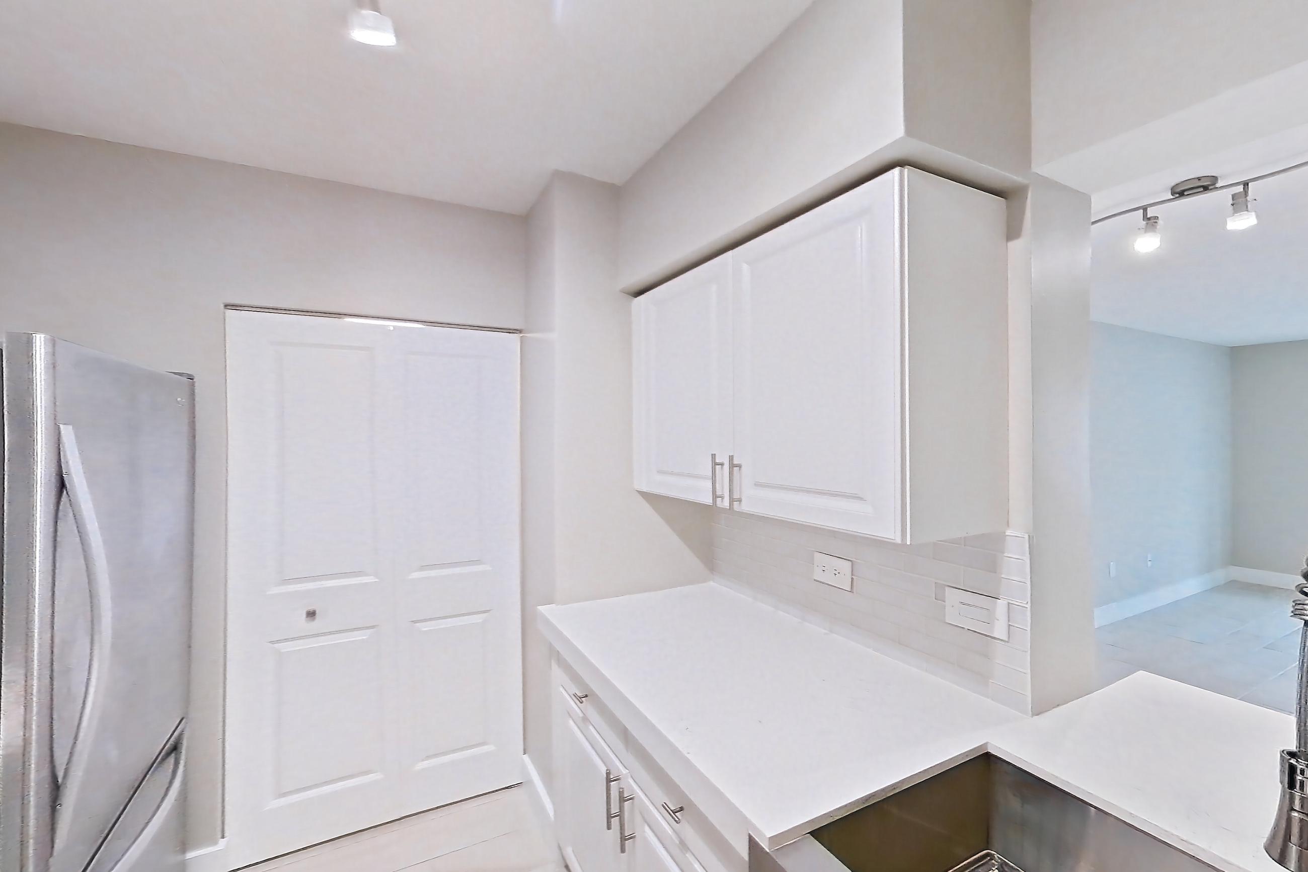 Kitchen with dishwasher, electric range, light countertops, light stone countertops, light tile flooring, light wood-finish flooring, oven/range, refrigerator, stainless steel appliances, and wood-look tile flooring, Apartment 0210 at Sunrise Harbor