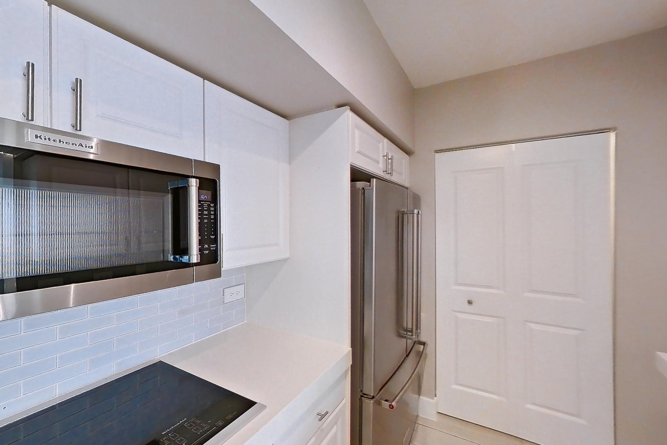 Kitchen with dishwasher, light countertops, light stone countertops, light tile flooring, light wood-finish flooring, oven/range, refrigerator, stainless steel appliances, and wood-look tile flooring, Apartment 1706 at Sunrise Harbor